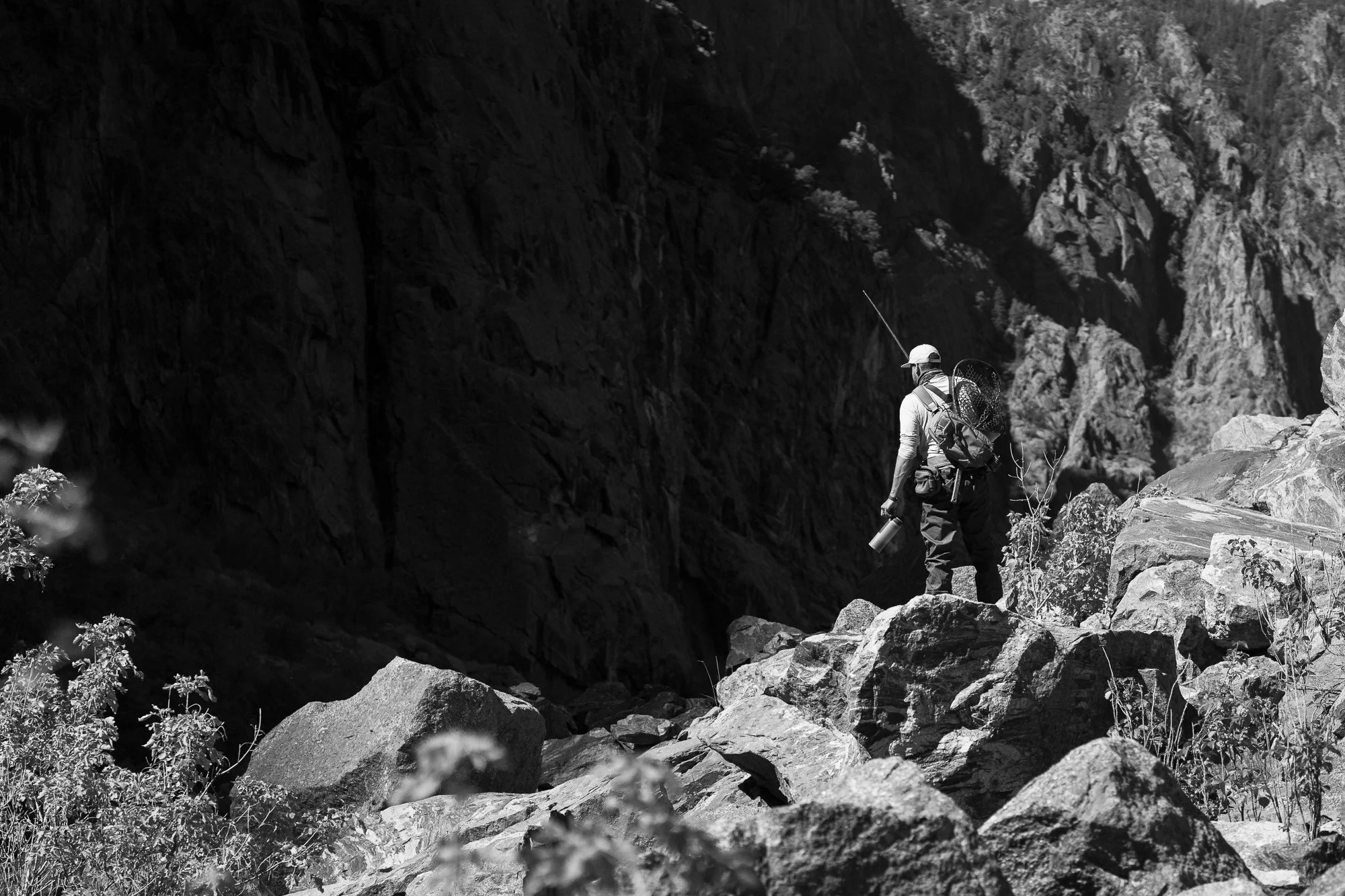 A fly angler stands on rocky terrain inside the Black Canyon of the Gunnison