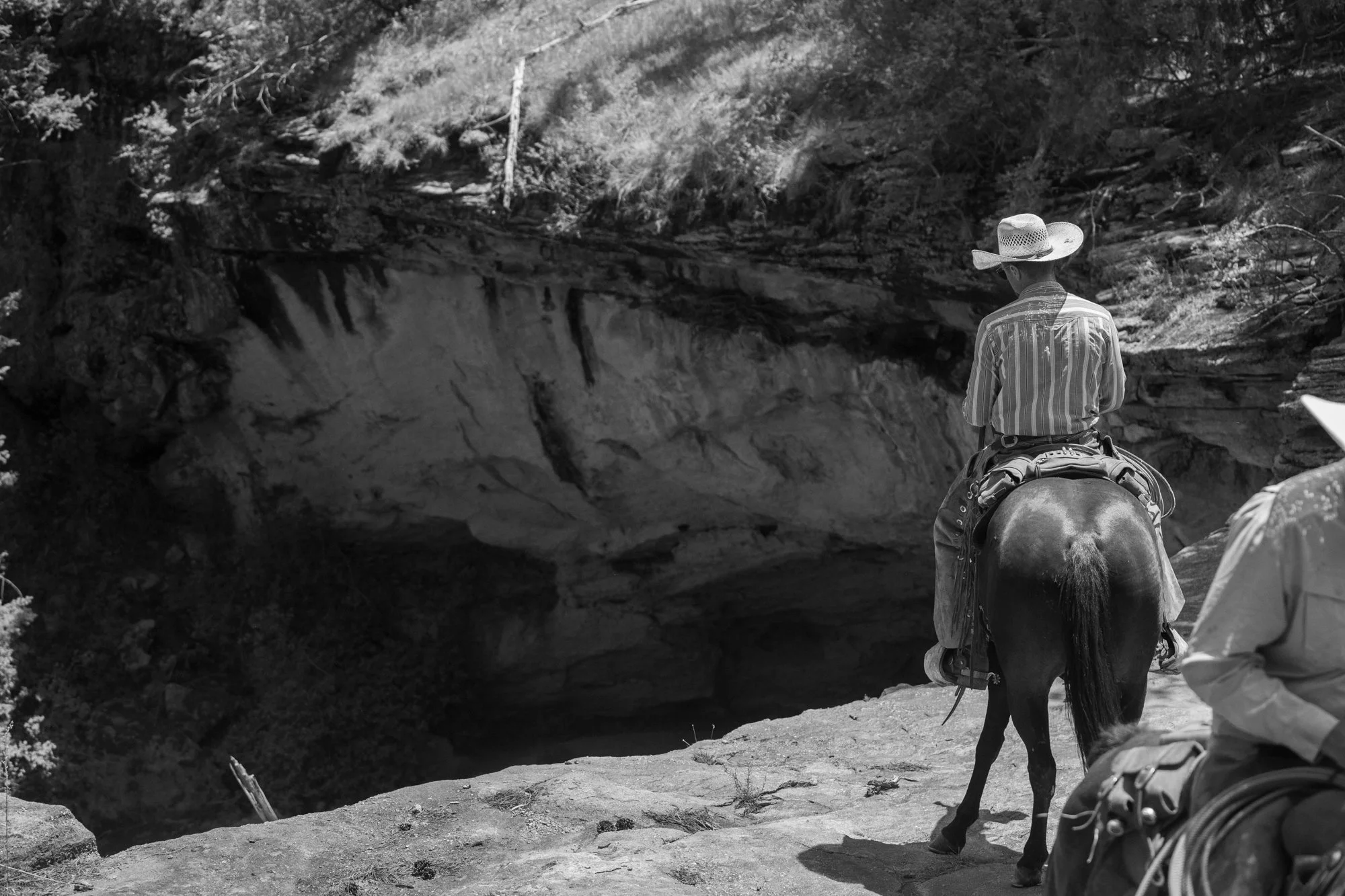 Cowboys on horseback pause beside a rocky overlook at Silver Spur Ranch in Colorado