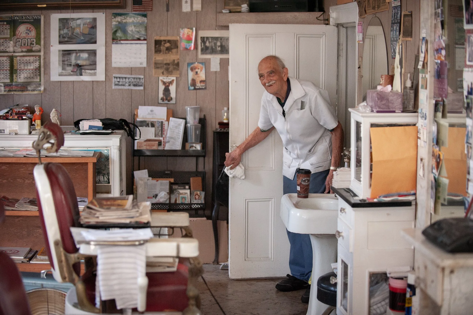elderly barber Tony cleaning inside his Greenwich Connecticut barbershop interior