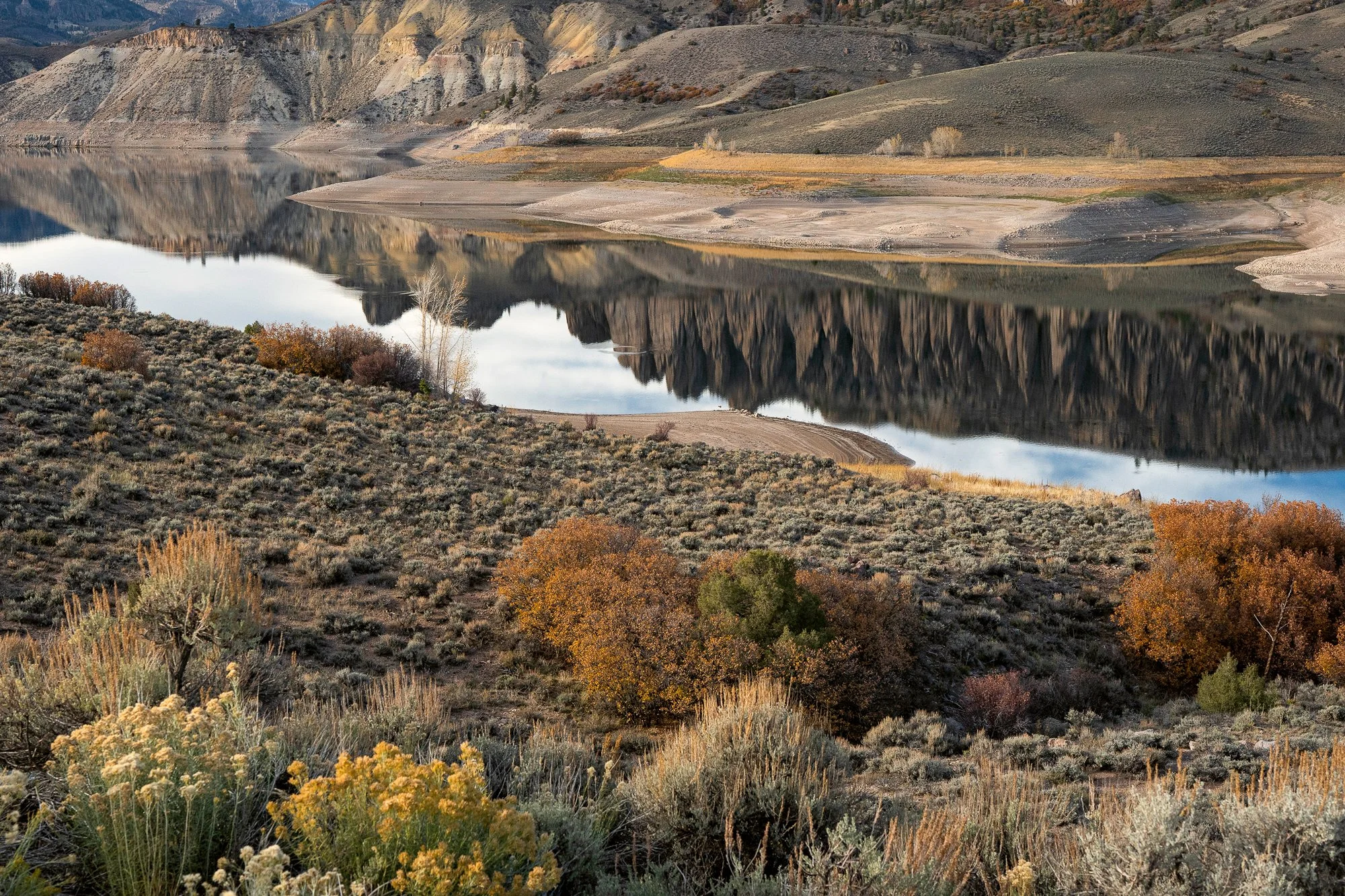 Calm river reflecting hills and autumn vegetation in rural western landscape