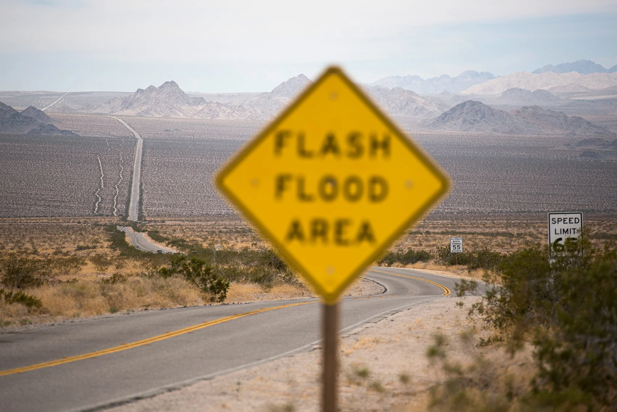 Flash flood area sign on a desert road with mountains across the California landscape