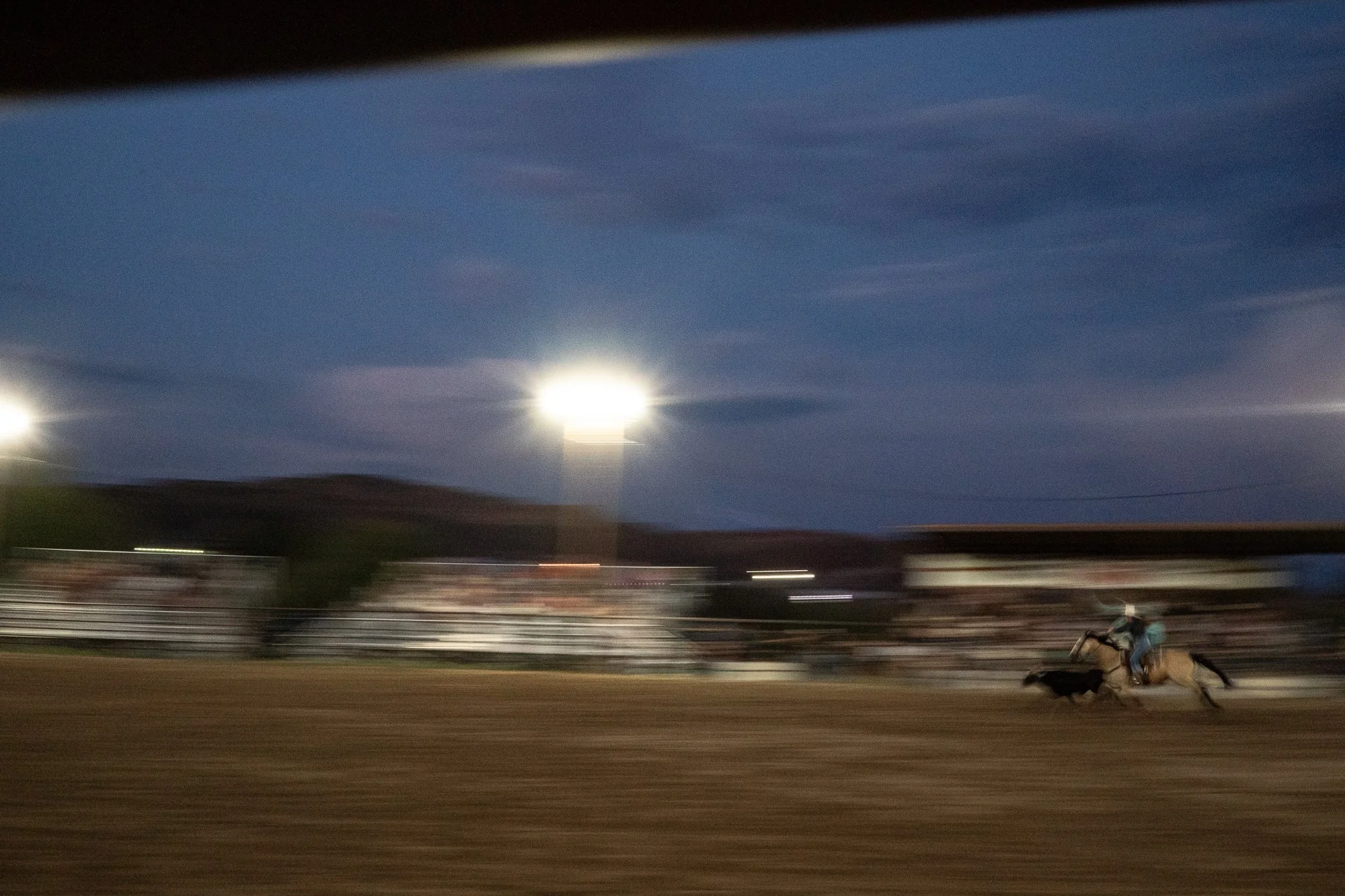 Team ropers pursue a steer under the arena lights during the Dubois Rodeo in Wyoming