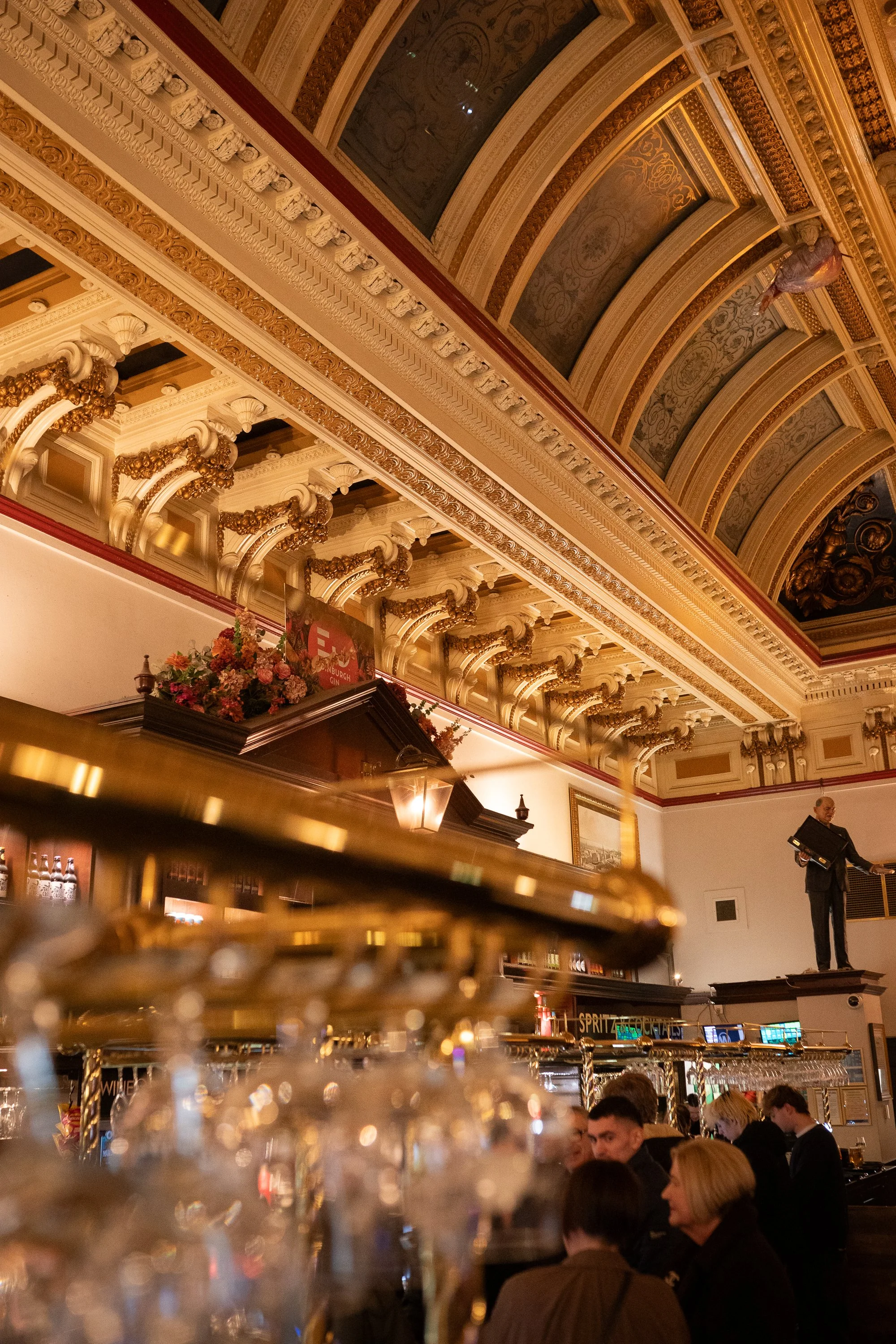 Ornate ceiling and crowded bar interior at The Standing Order in Edinburgh