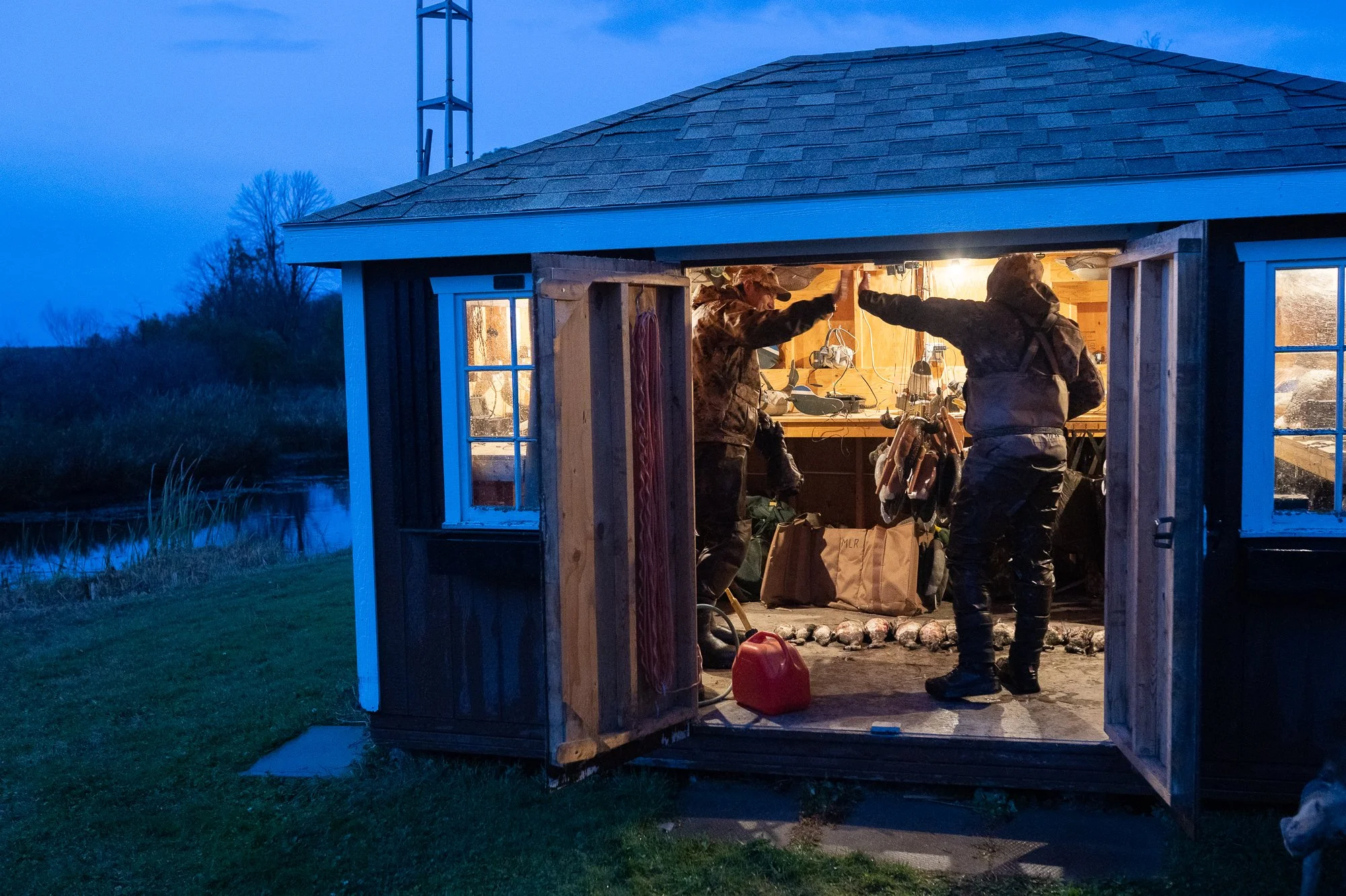 Duck hunters prepare gear inside a marsh outbuilding before sunrise during hunting season in Ontario