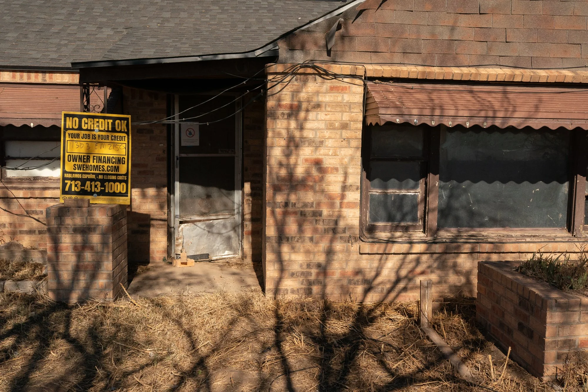 Brick house in rural Texas with an owner financing sign on the Llano Estacado