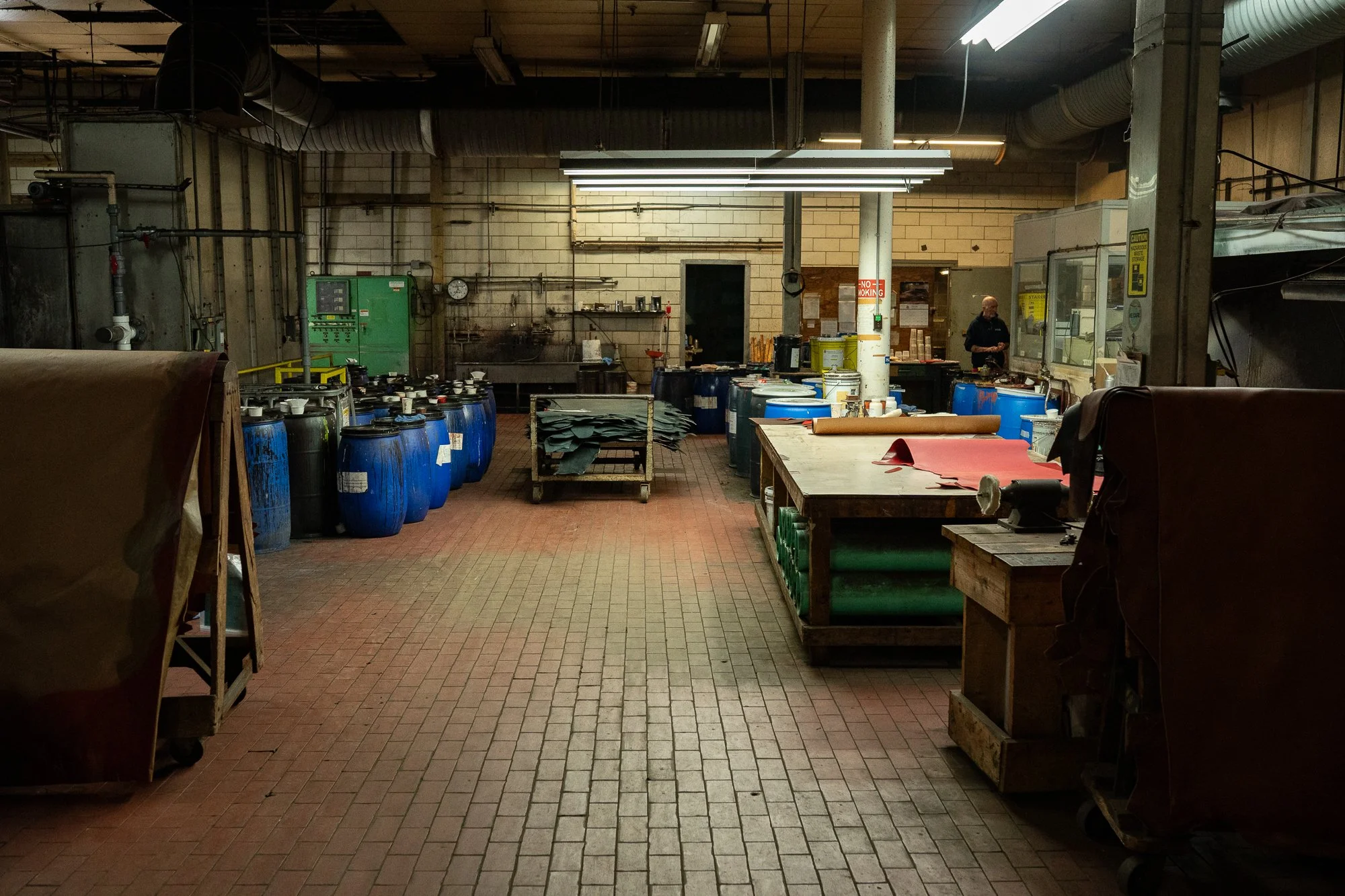 Interior of the Wickett & Craig tannery with leather, work tables, barrels, and industrial equipment on the production floor