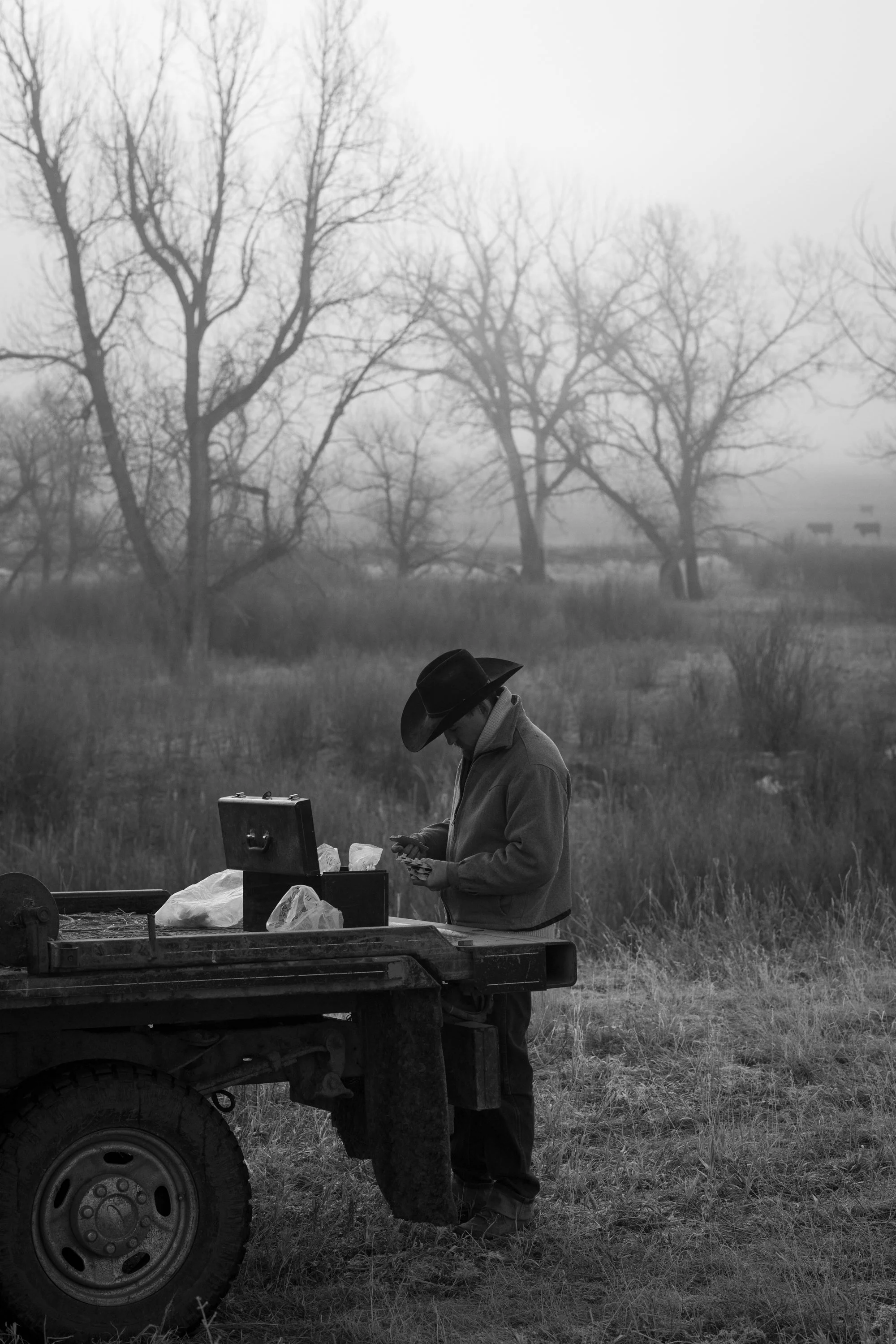 A cowboy prepares supplies from the back of a ranch truck on a foggy morning at Silver Spur Ranch in Colorado
