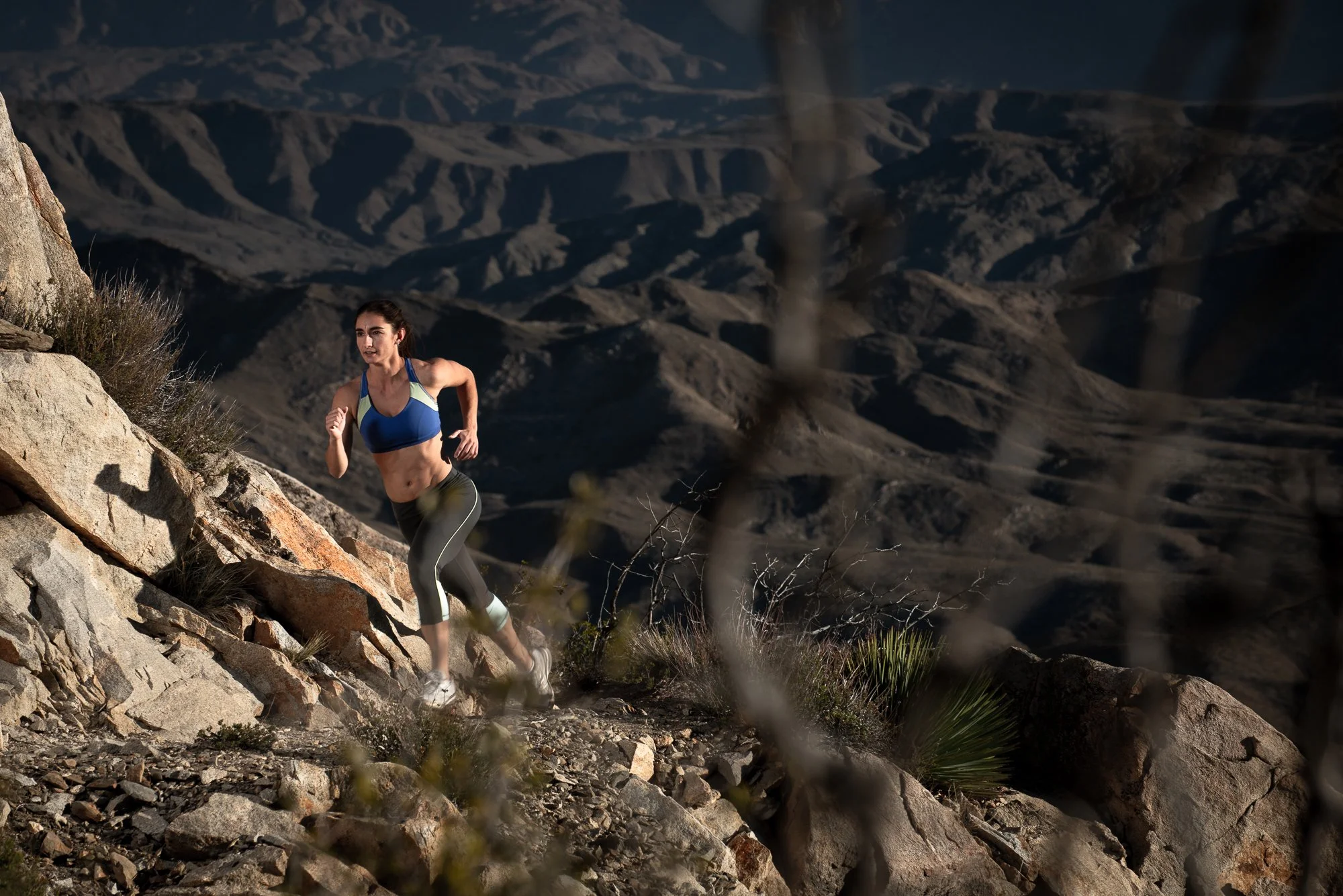 Female trail runner navigating rocky mountain terrain