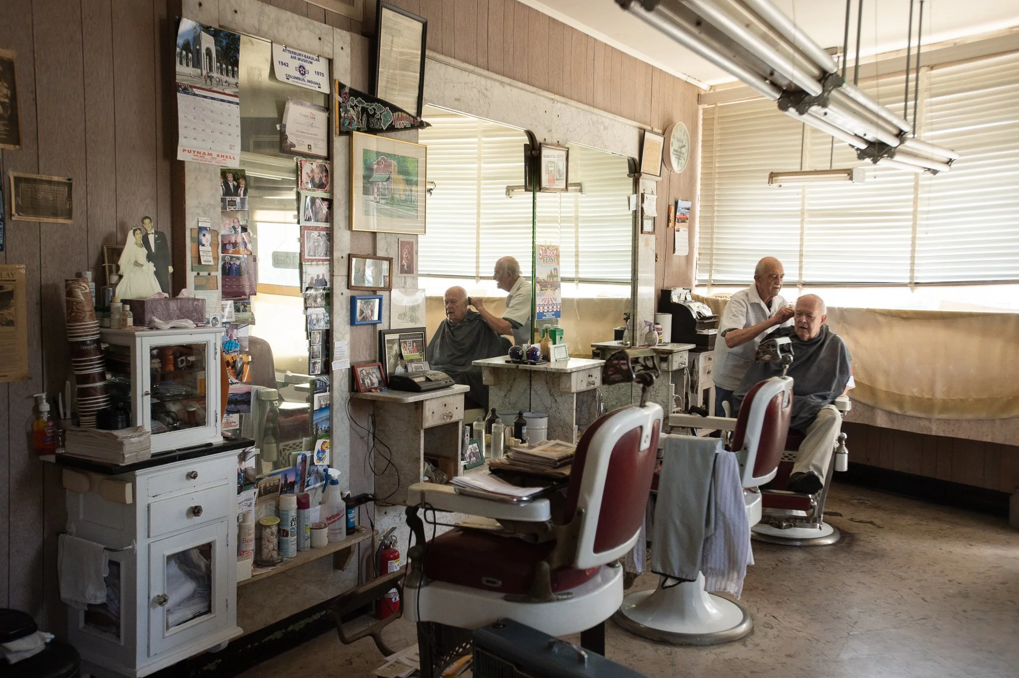 wide interior of Tony's Barbershop in Greenwich Connecticut showing vintage barber chairs and mirrors during a haircut