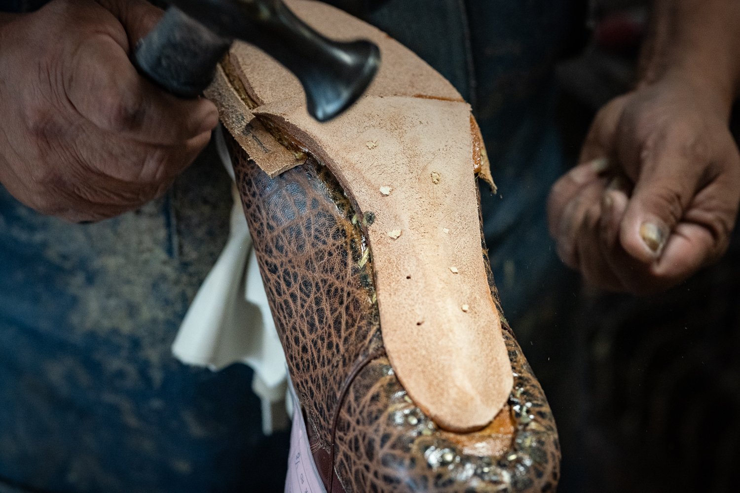 Bootmaker hammering leather sole onto a handmade cowboy boot at ML Leddy’s