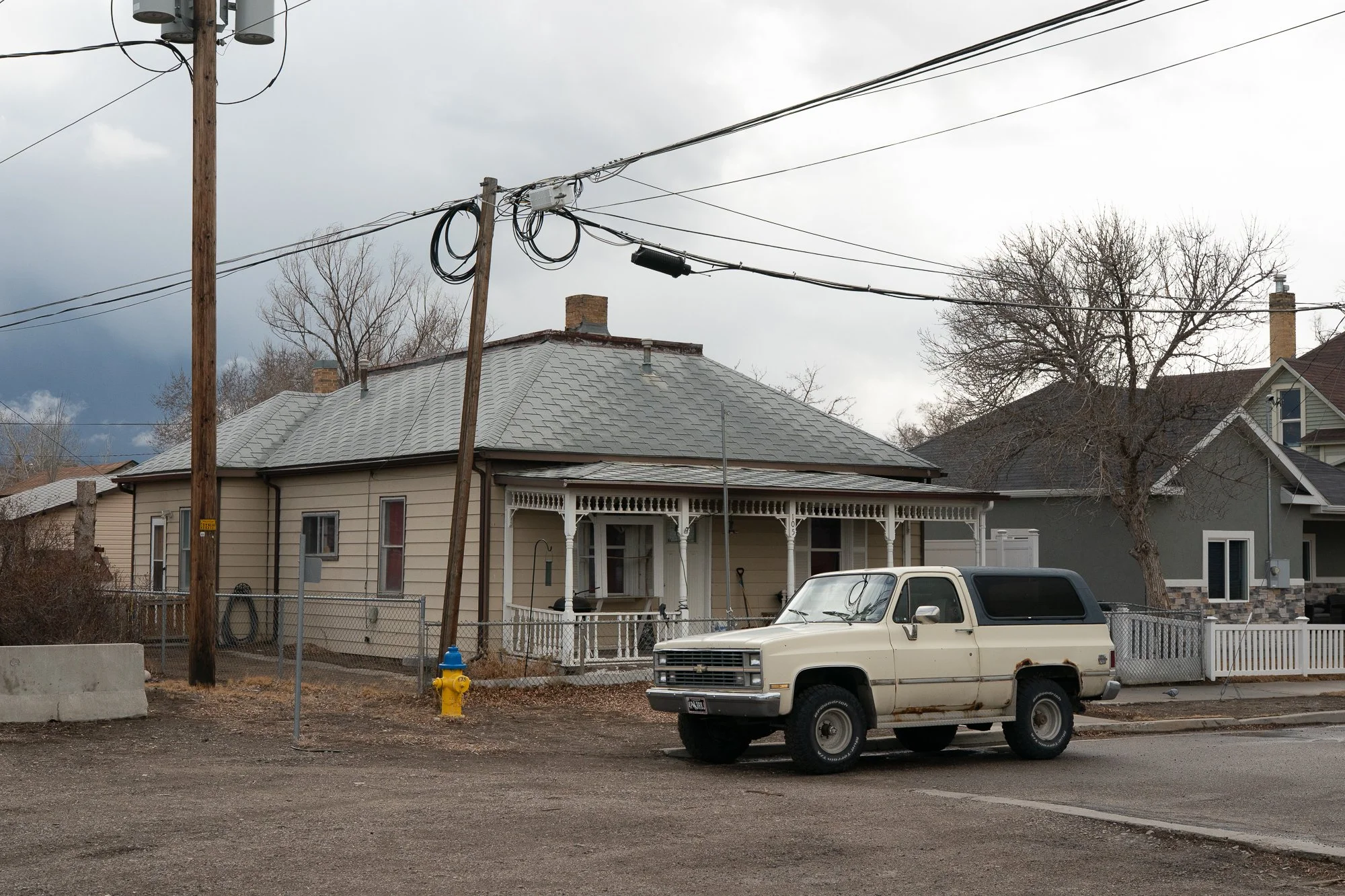 Older pickup truck parked at a residential corner beside a small house in Rock Springs Wyoming