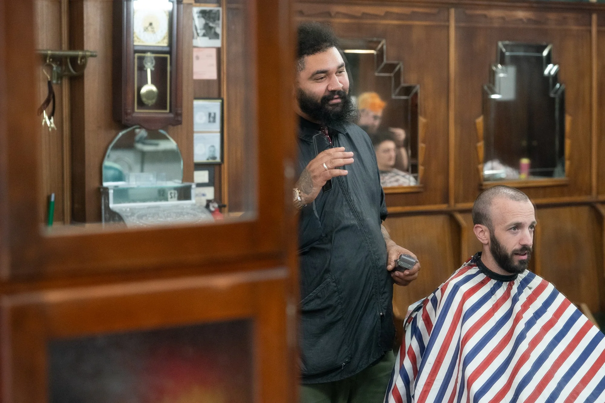 Barber standing with clippers beside a client at Patsy’s Barbershop in Albany New York