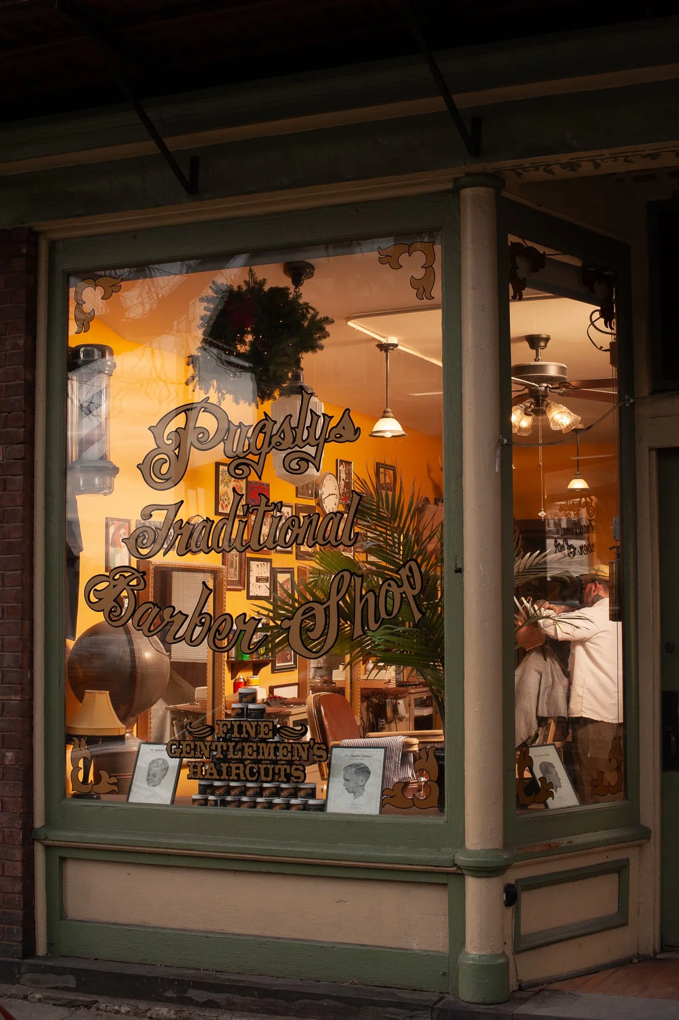 Exterior view of Pugsly’s Traditional Barber Shop in Kingston, New York, with the barbershop visible through the front windows.