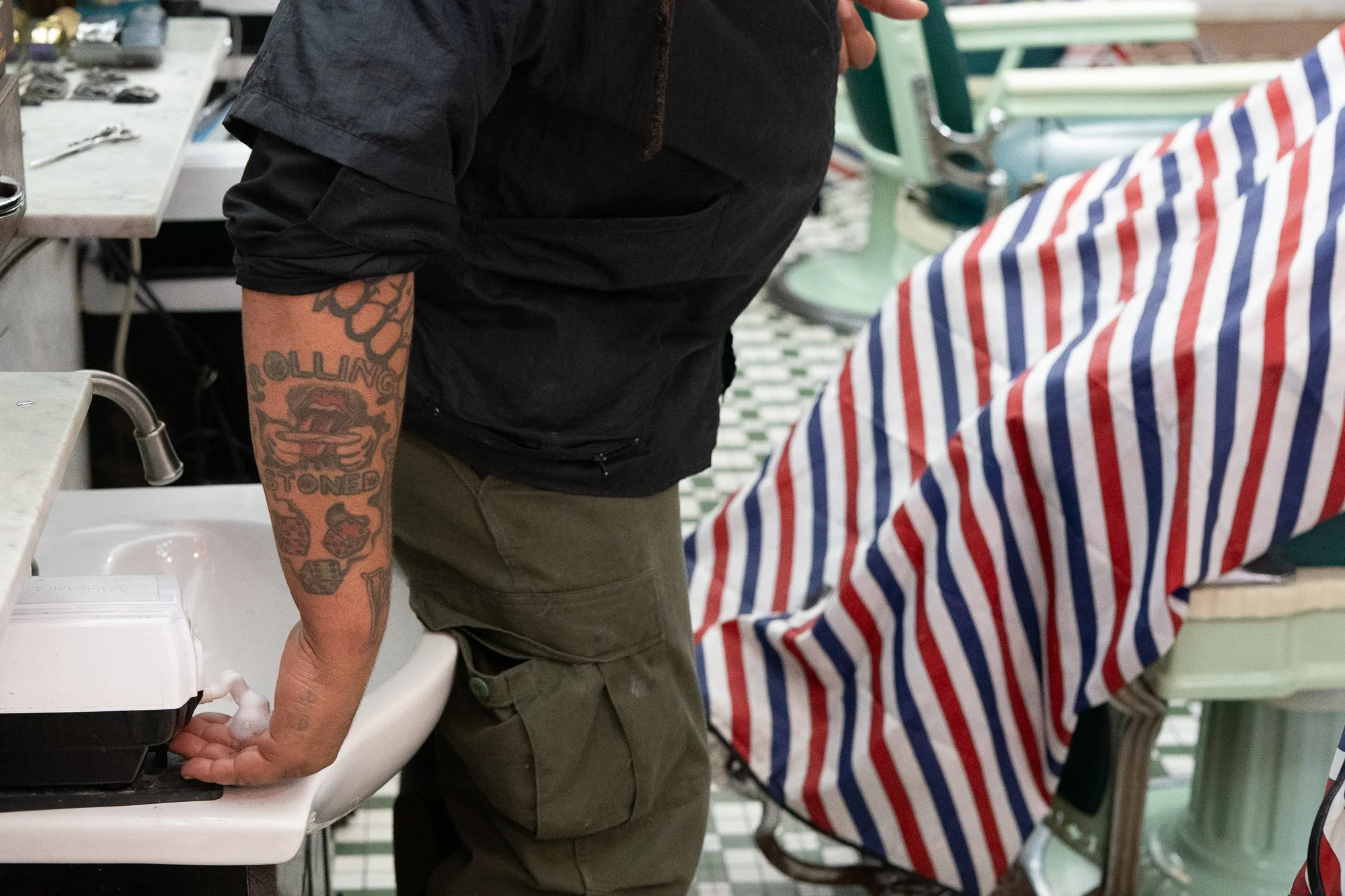 Barber moving between the sink and chair during a service at Patsy’s Barbershop in Albany New York