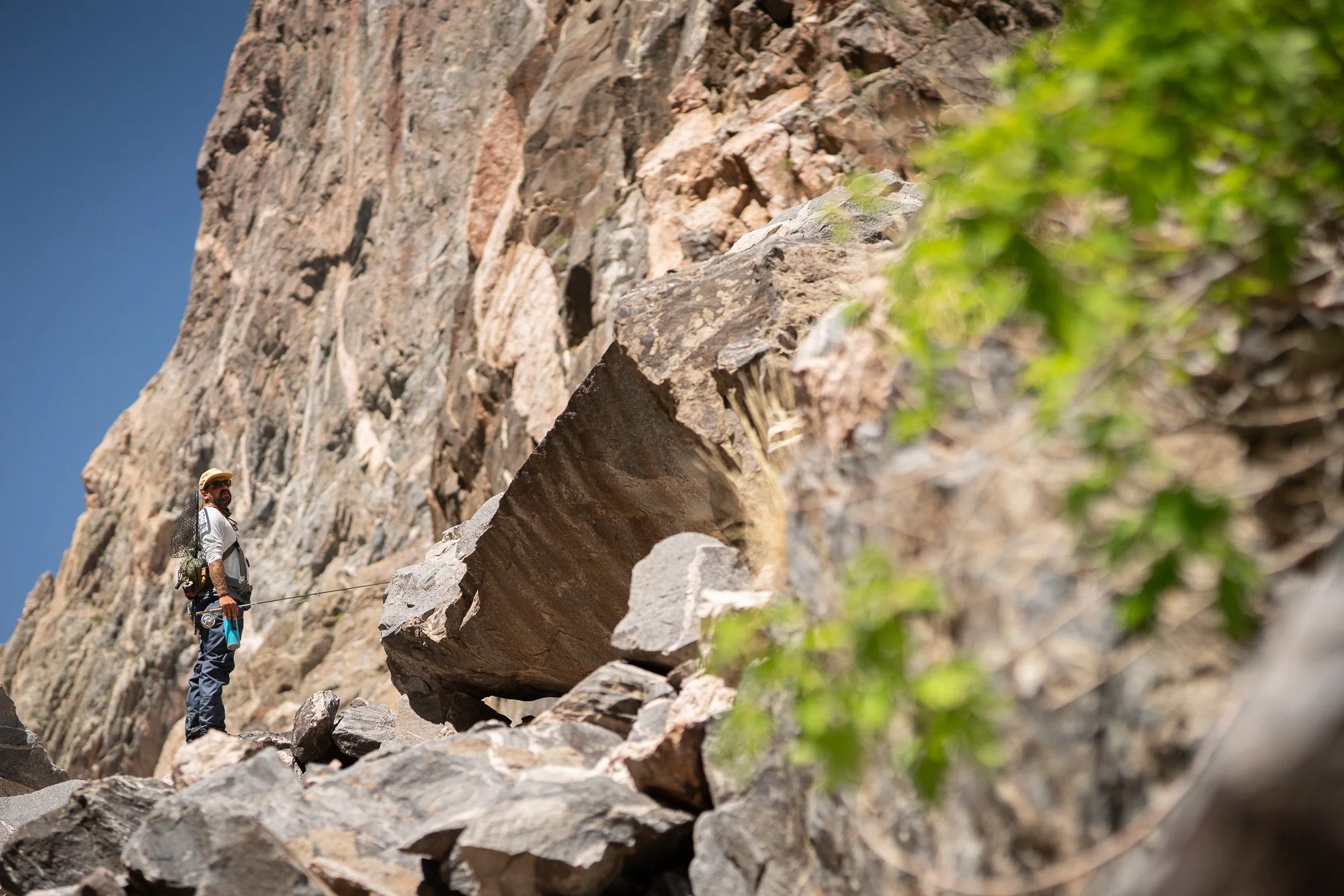 A fly angler stands beneath steep canyon walls in the Black Canyon of the Gunnison