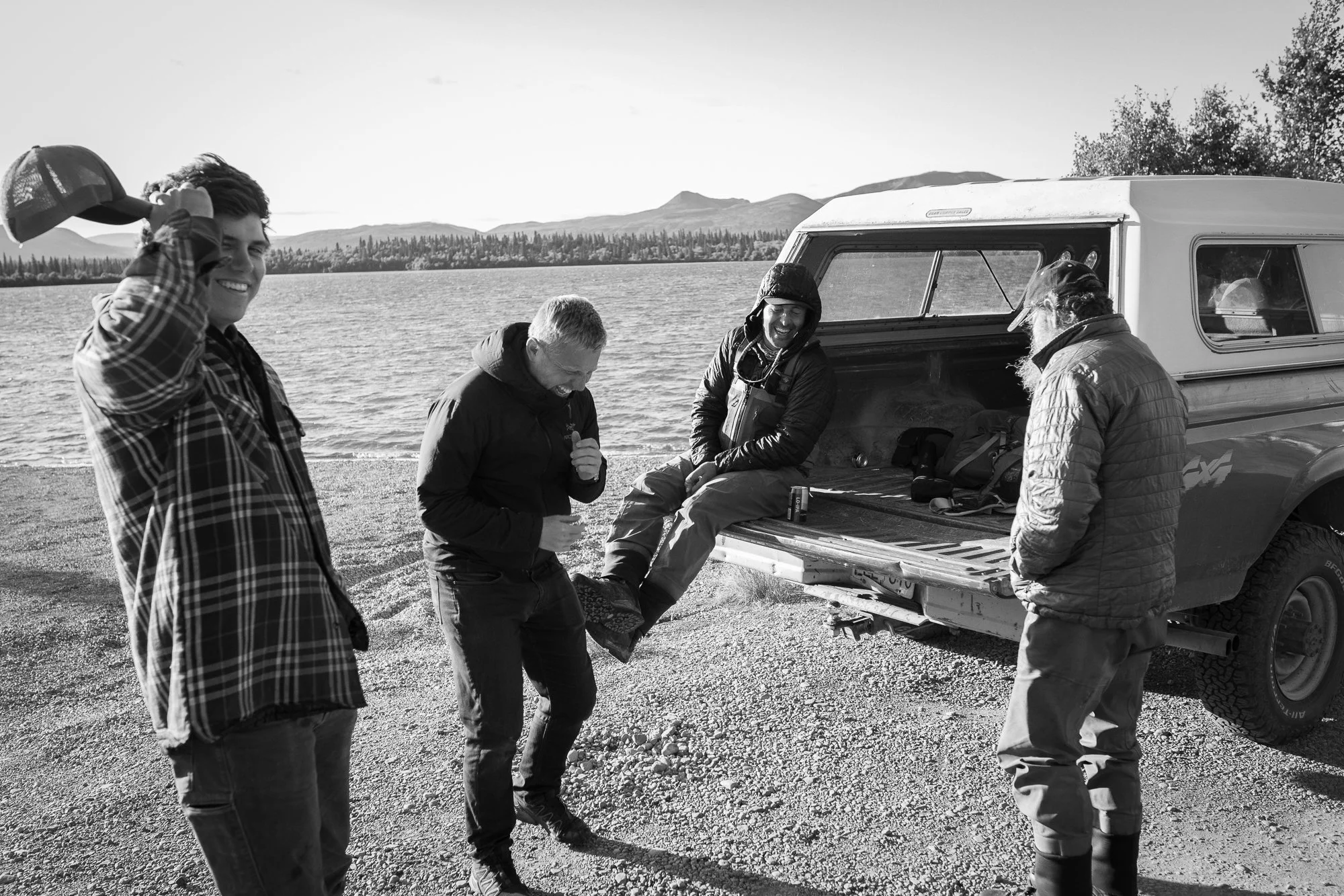 Group of anglers gathered beside a truck along an Alaskan lake