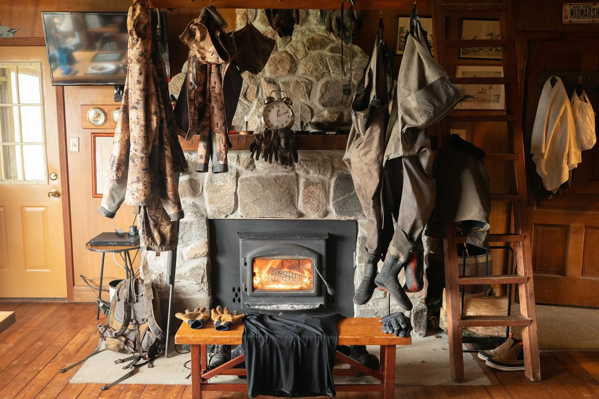 Duck hunting waders and gear dry beside a wood stove inside a hunting lodge in Ontario