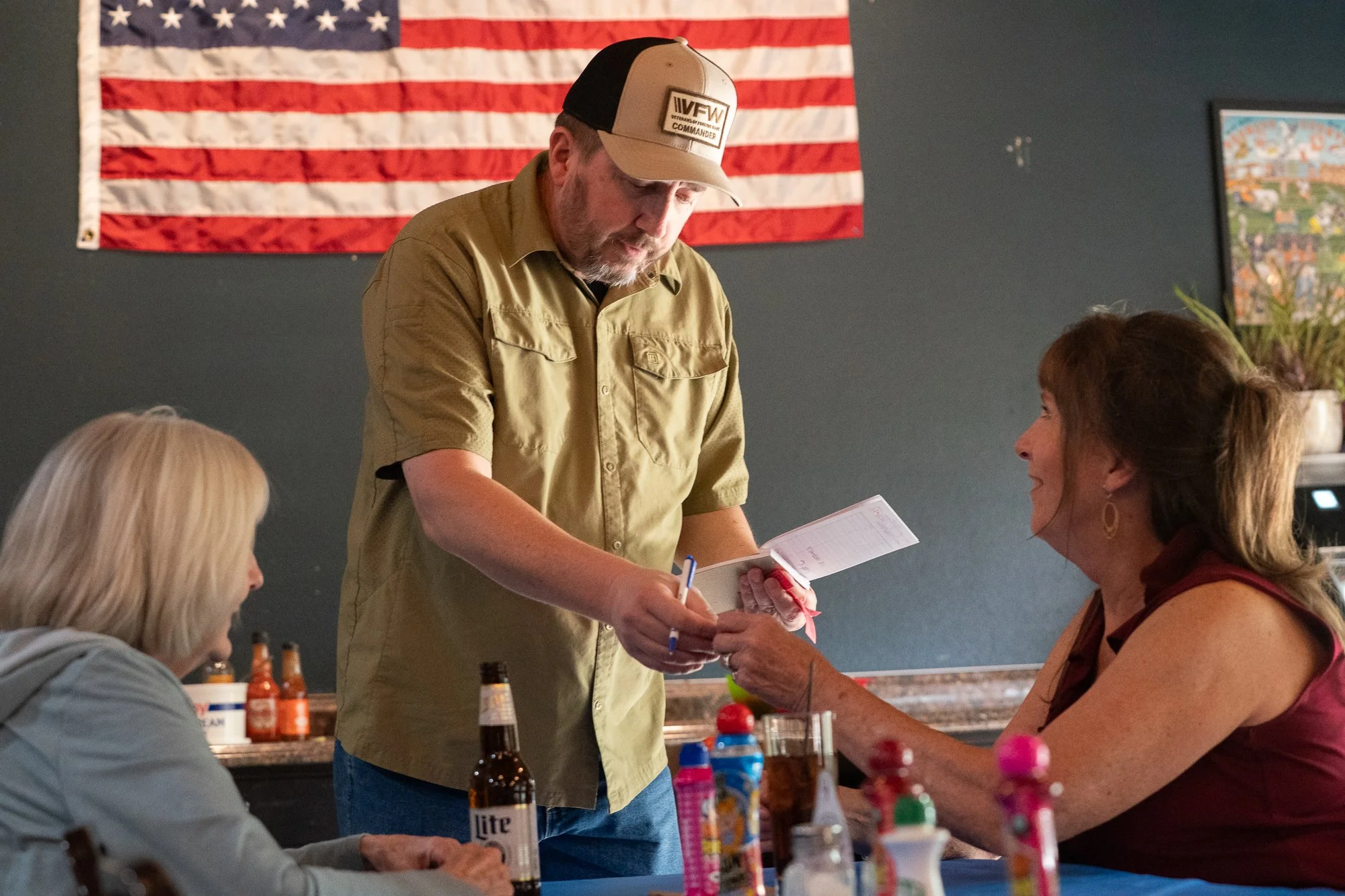 Veterans gathered at a table inside a VFW hall with an American flag on the wall