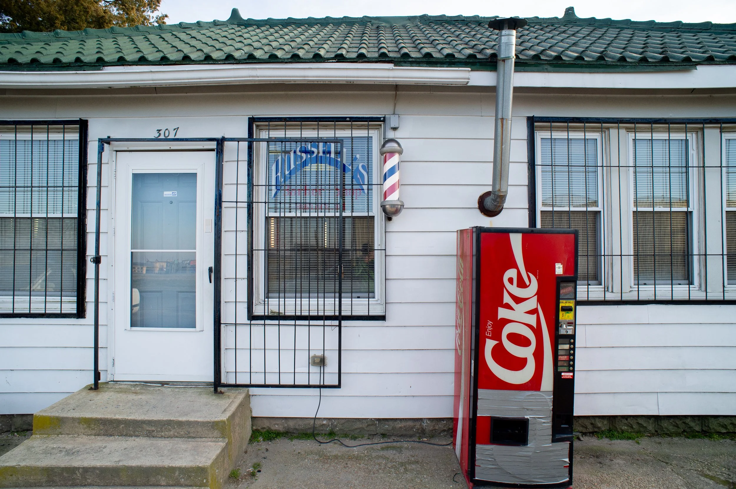Exterior of Russell’s Barbershop in Hurlock Maryland with a Coca-Cola vending machine outside