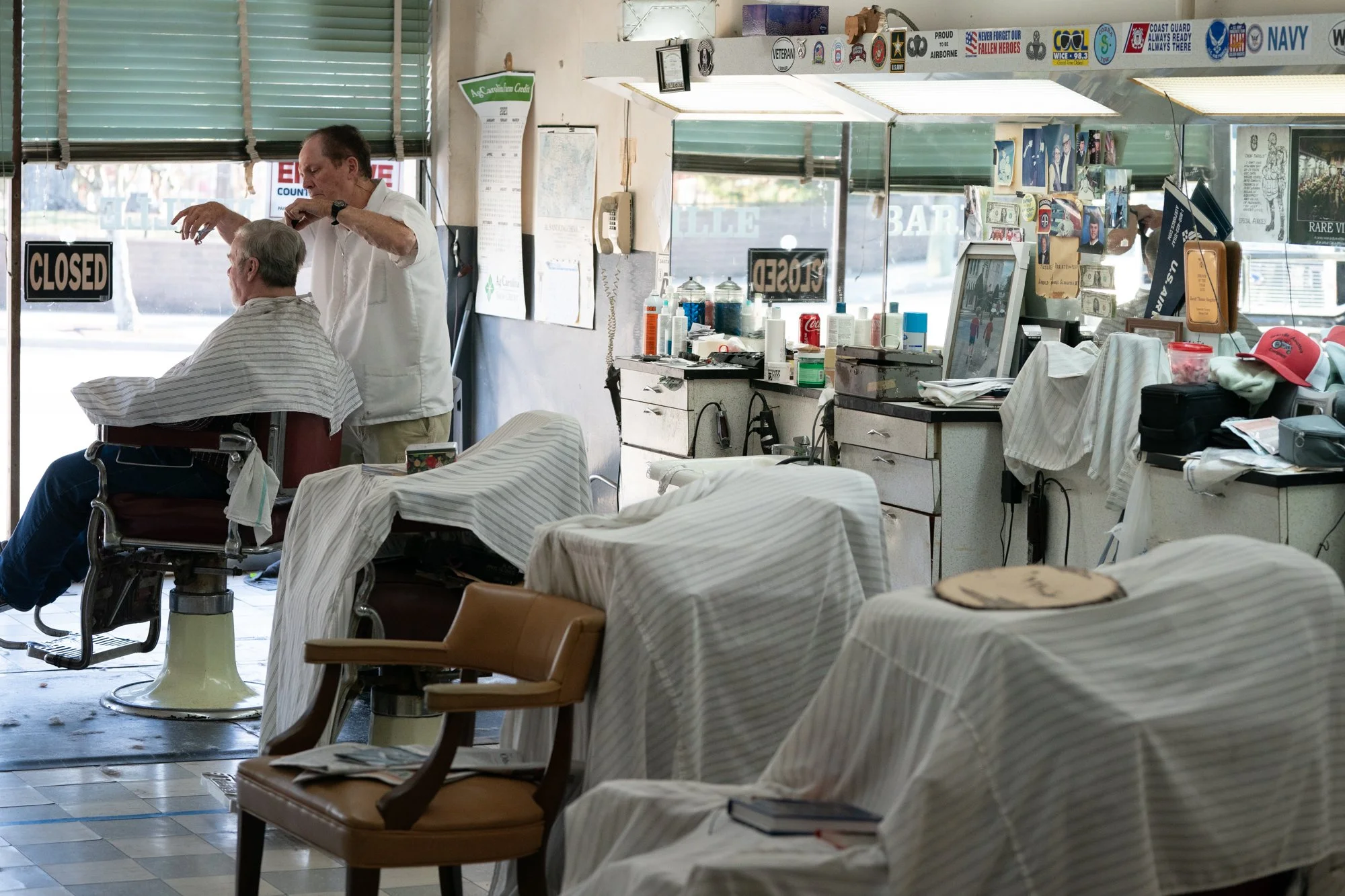Documentary photograph of a barber cutting hair inside a small-town North Carolina barbershop