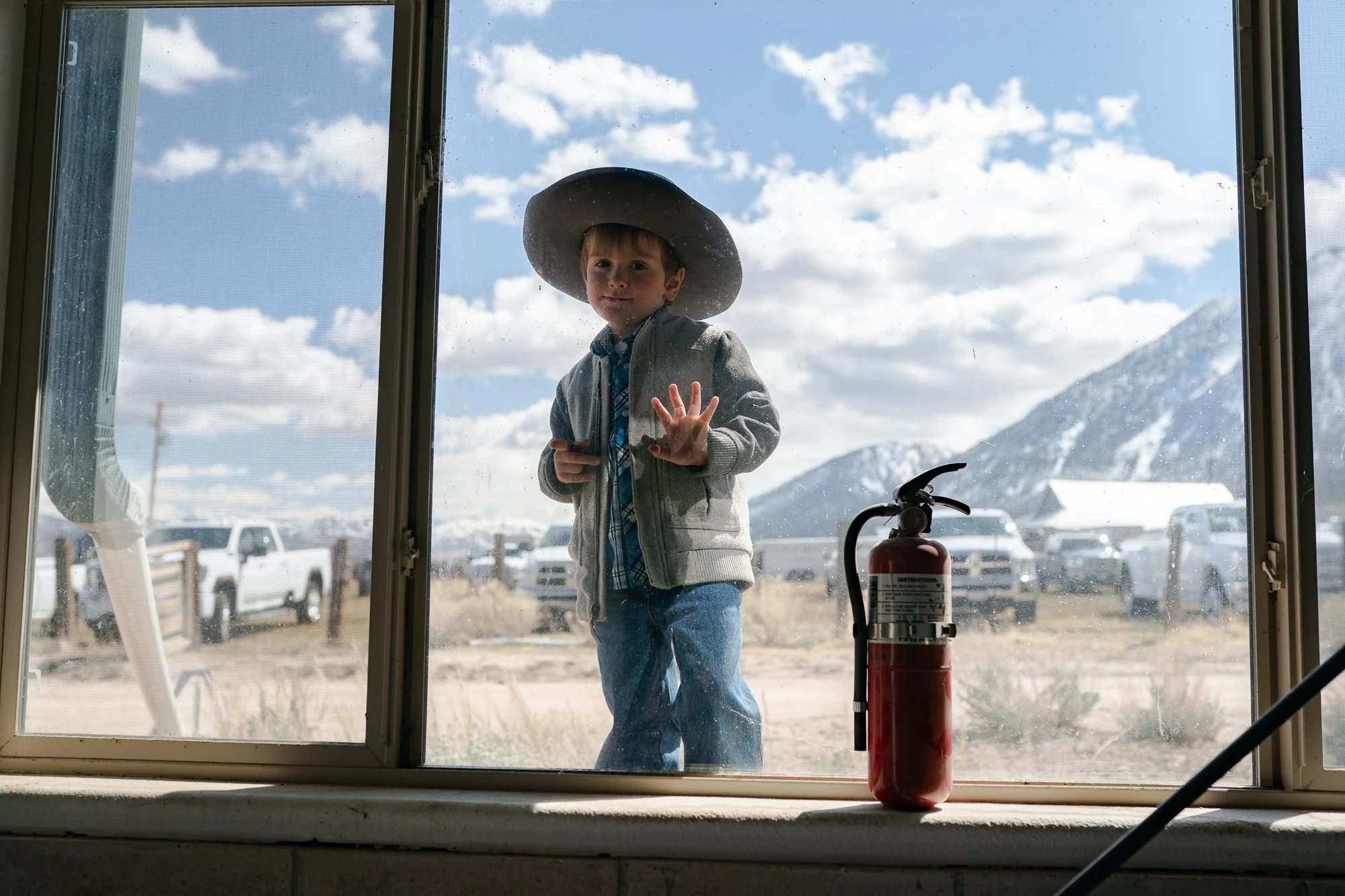 Young boy in a cowboy hat standing outside a window at a Nevada bull sale