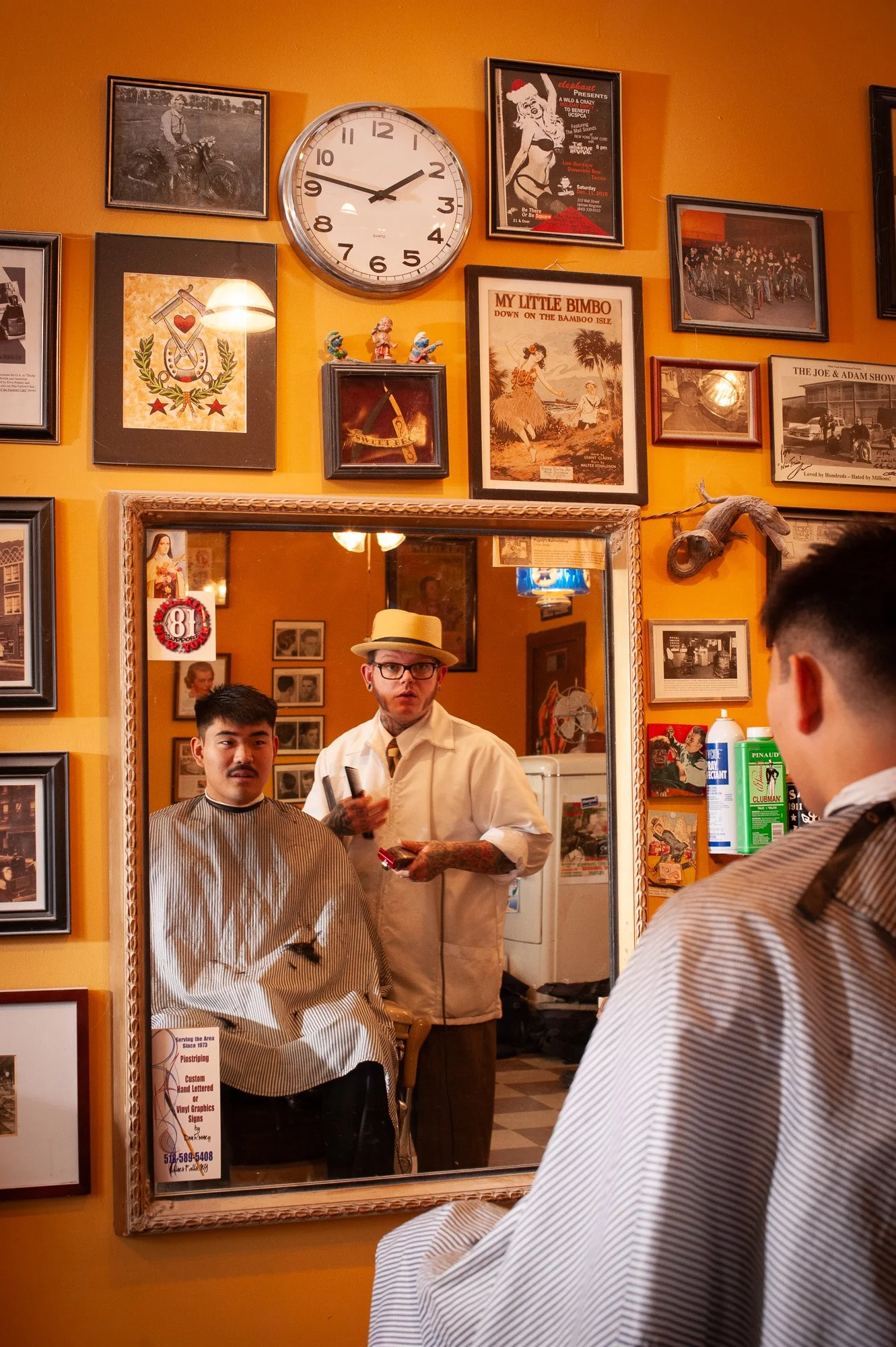 Barber cutting a client's hair inside Pugsly's SideShow Barbershop in Kingston, New York.