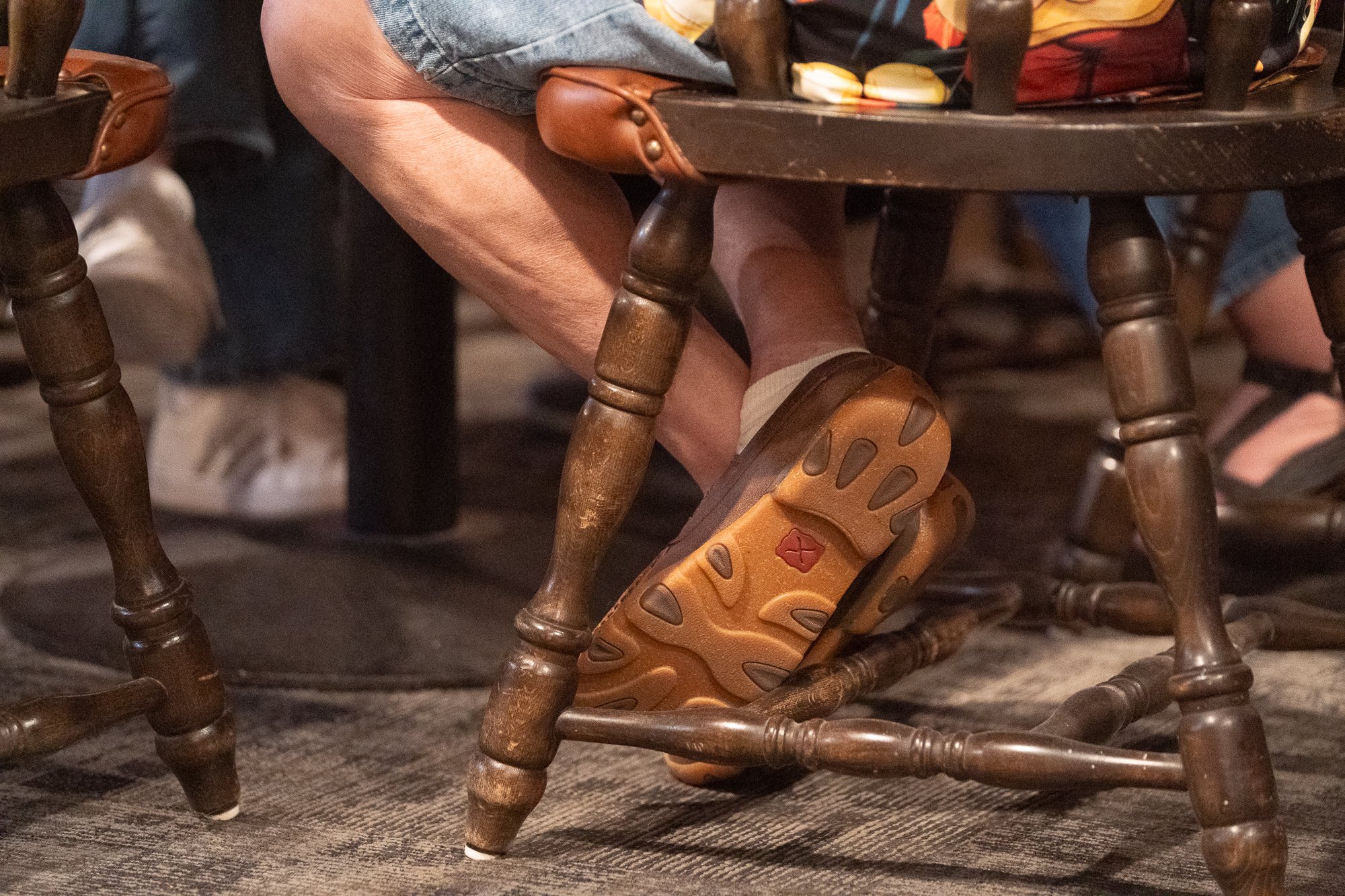 Twisted X shoe beneath a wooden chair inside a VFW hall during a veterans brand campaign