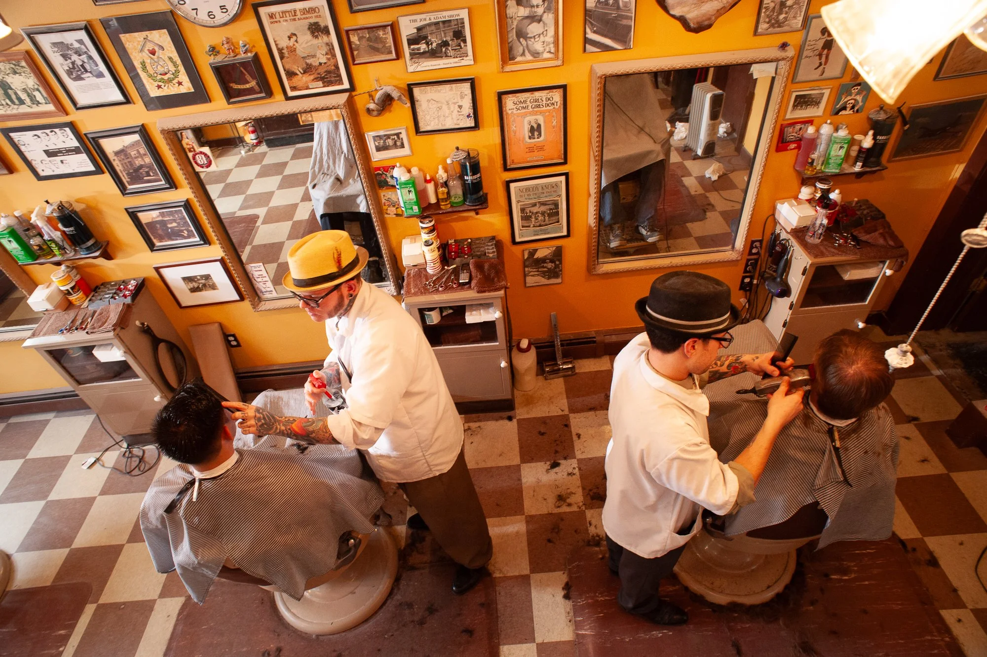 Two barbers cutting clients' hair inside Pugsly's SideShow Barbershop in Kingston, New York.