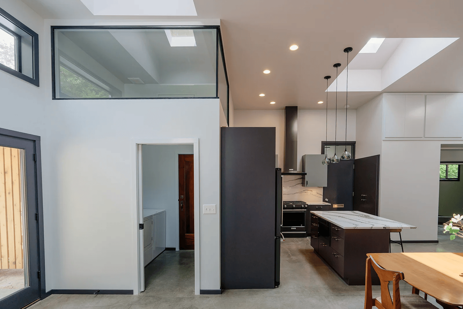 Dark kitchen cabinetry, pendant lights, and glass partitions in the Vashon Hangar Home