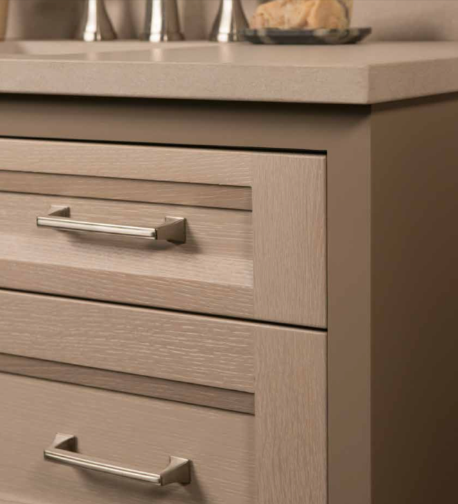 Close-up of a modern kitchen cabinet with two drawers and silver handles, part of a granite countertop.