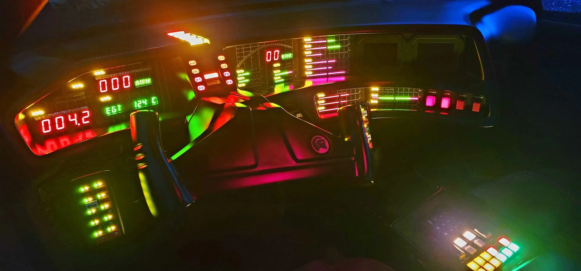 Dashboard of a futuristic or sci-fi vehicle with numerous colorful digital meters, dials, and indicator lights, displaying various readings and information.