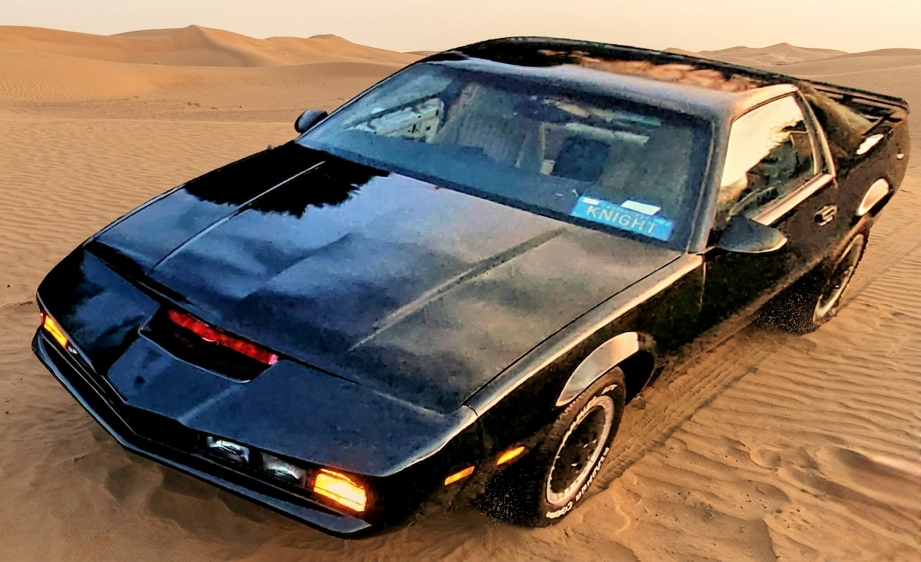 Knight Rider KITT Car  black High Tech AI Supercar parked on sand dunes in the desert during sunset.