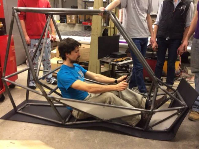 Mike Jastram trying out the (eventual location of the) driver's seat and holding onto a very maneuverable wheel.