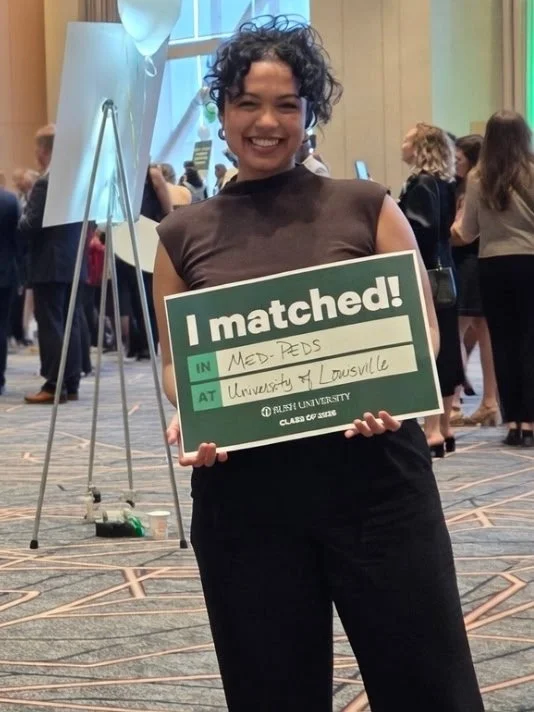 Woman with curly hair pinned up, holding I matched sign
