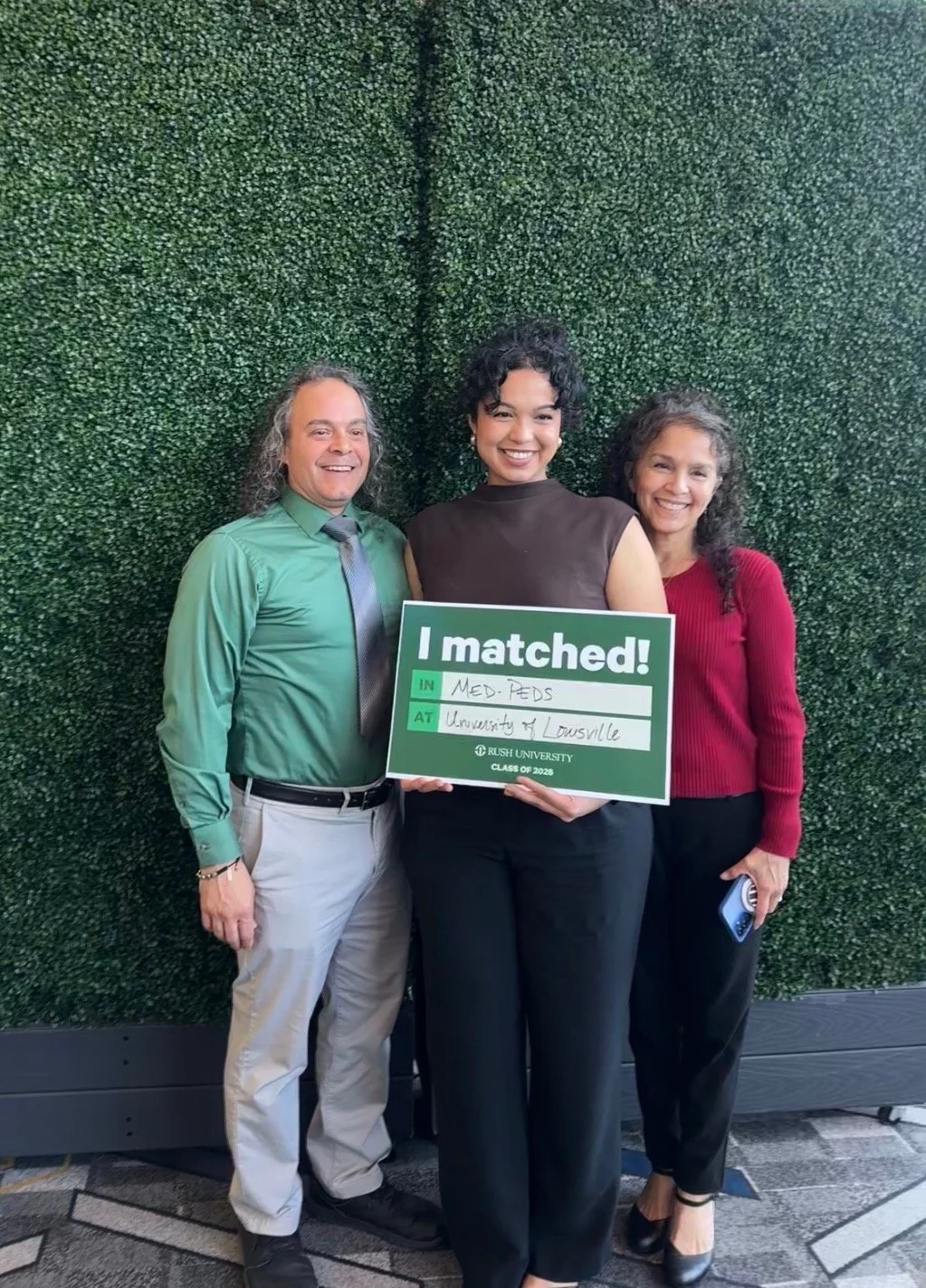 Woman with I matched sign standing with parents