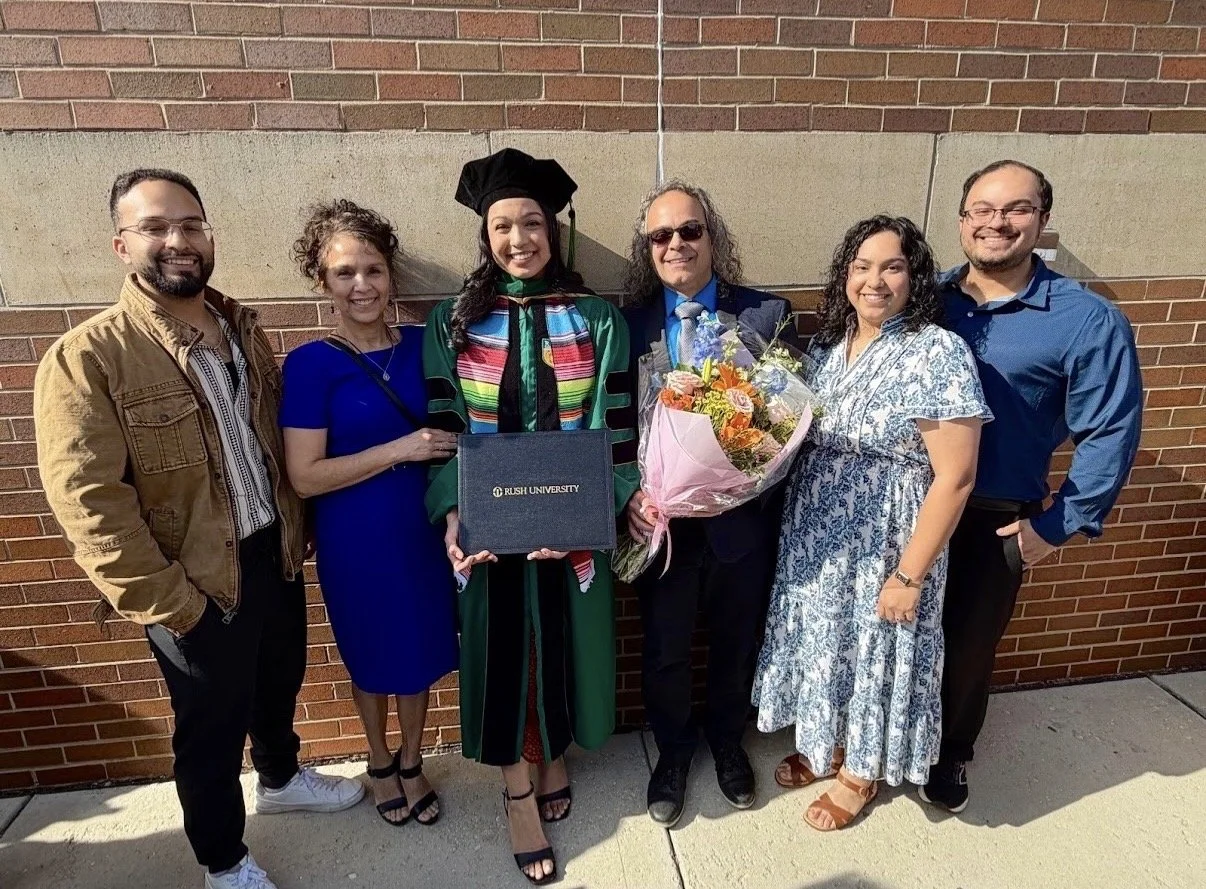 young woman in med school graduation cap and gown posing with family