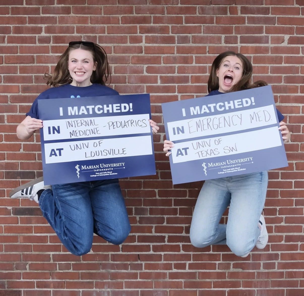 Two young women jumping in the air holding I matched signs