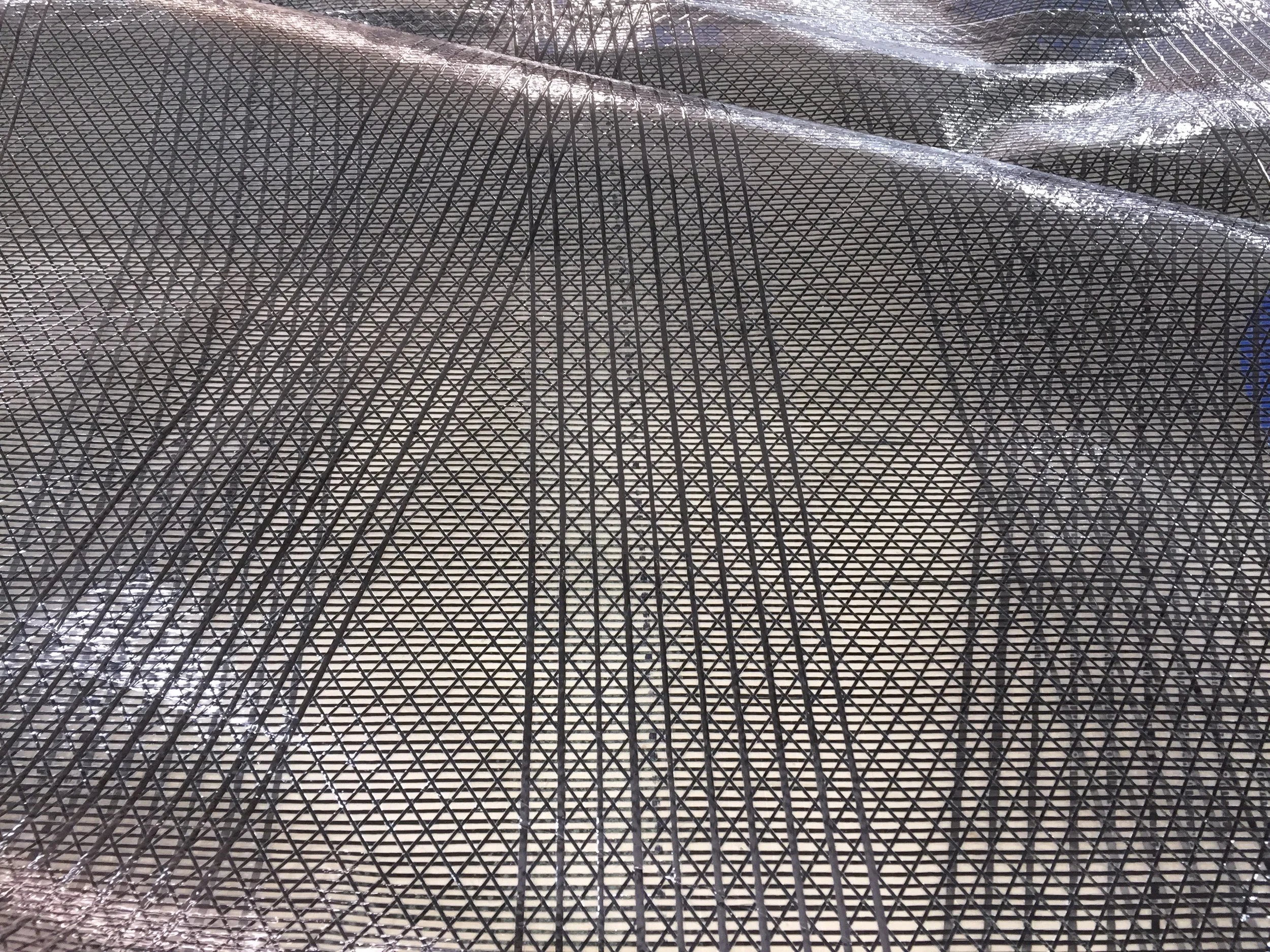 Close up of carbon X-Drive sail made with a black aramid laminate. Without a taffeta layer, the sail is see through.