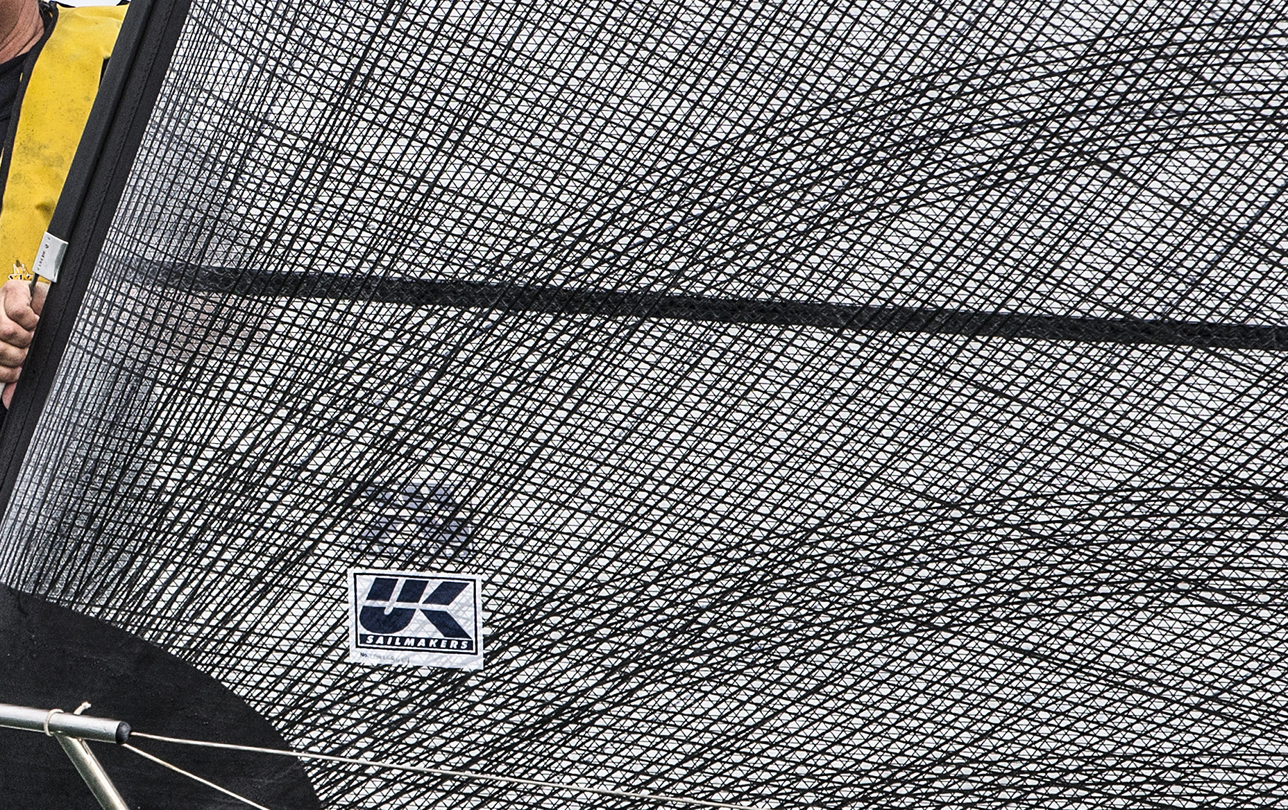 Close up of the carbon X-Drive fibers near the tack of a genoa. The dark horizontal line is the seam between panels. The X-Drive fibers are bonded to the sail across the seams, which prevents speed-killing seam-creep.