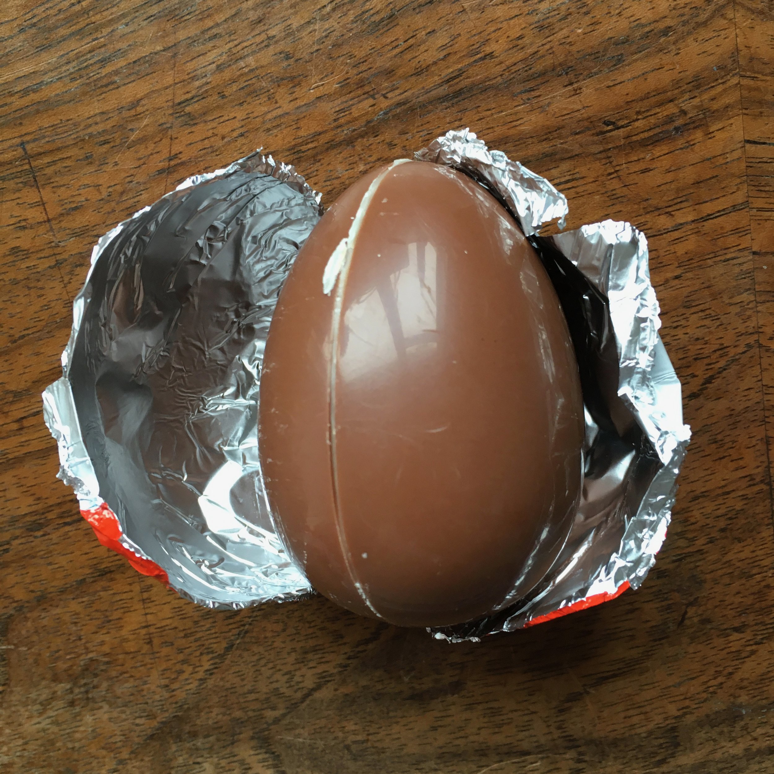  a Kinder Surprise egg, foil unwrapped to reveal the hollow chocolate egg within 