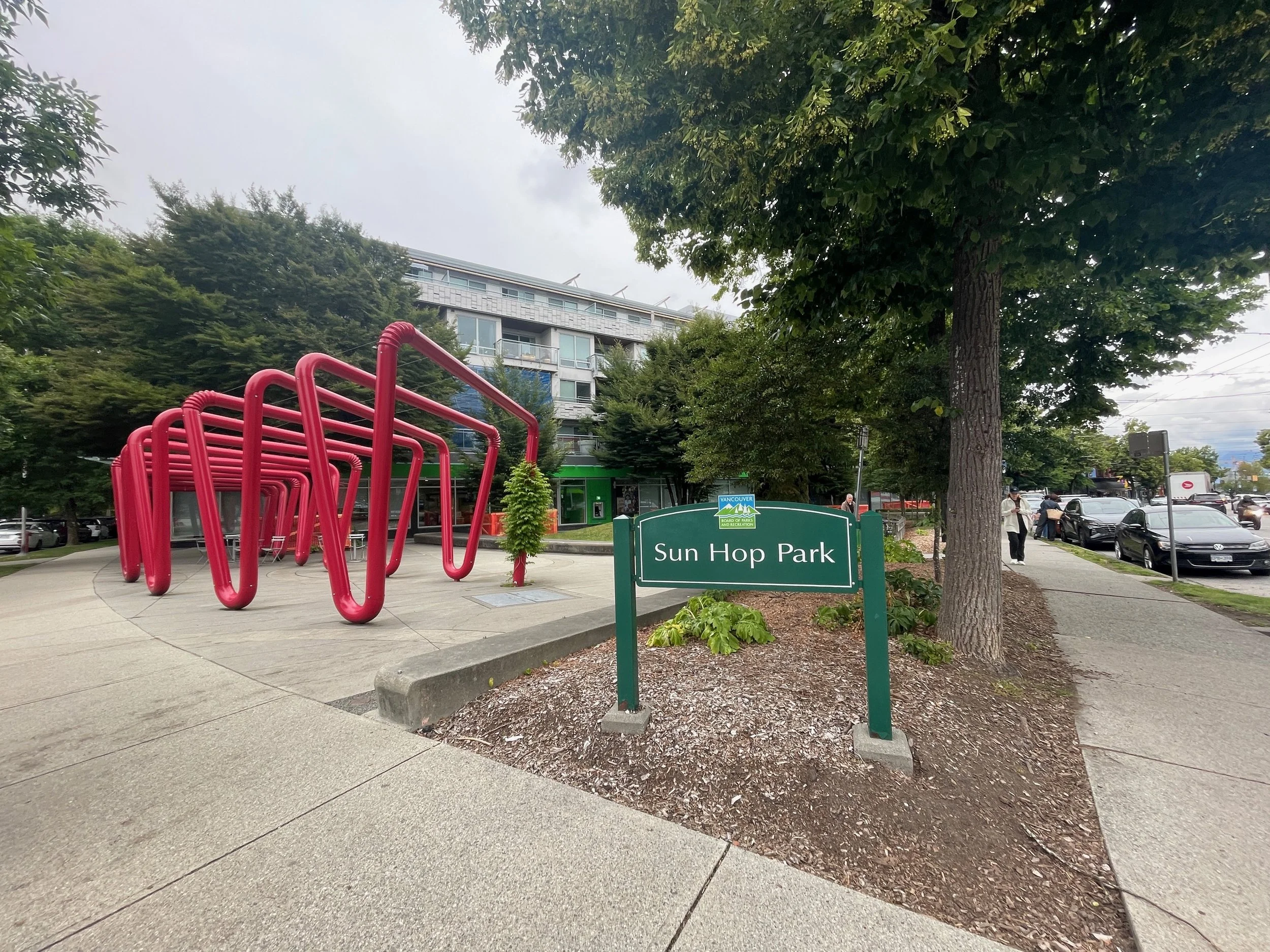   Sun Hop Park:  the green sign with the name of the park, next to it the installation of giant red bendy straws, and behind it the bank 