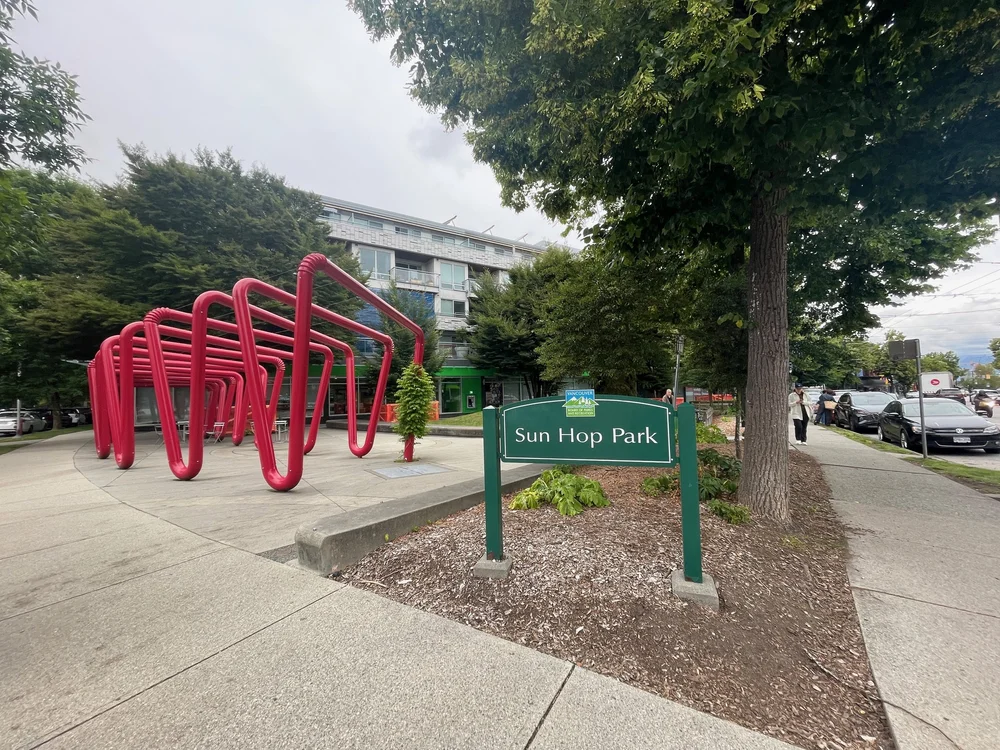   Sun Hop Park:  the green sign with the name of the park, next to it the installation of giant red bendy straws, and behind it the bank 