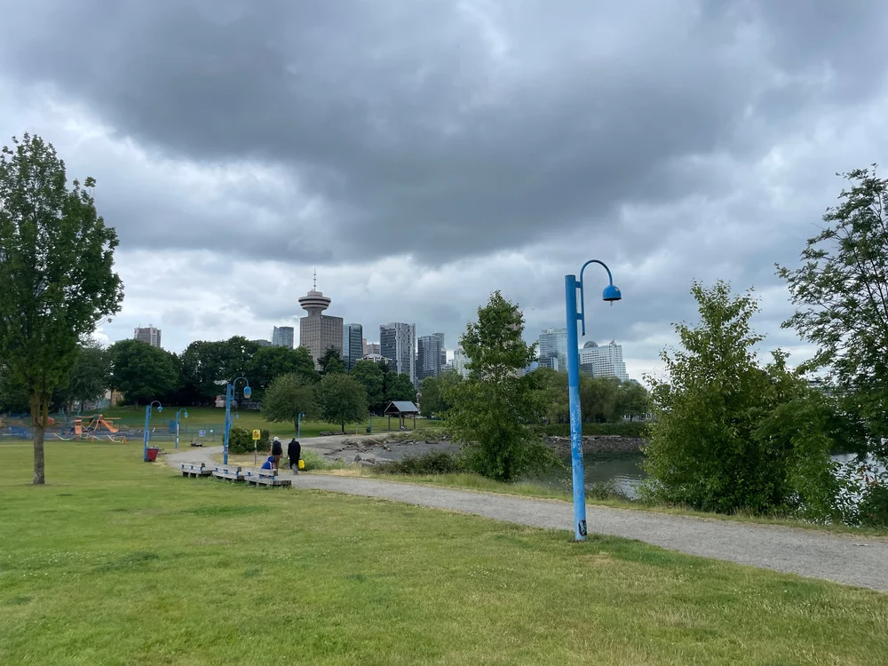   C.R.A.B. Park at Portside:  over on the side of the park that isn’t the port is an expanse of grass, some trees, blue lampposts, a small playground, a grey beach and beyond the buildings of downtown Vancouver, perched atop one is the revolving rest