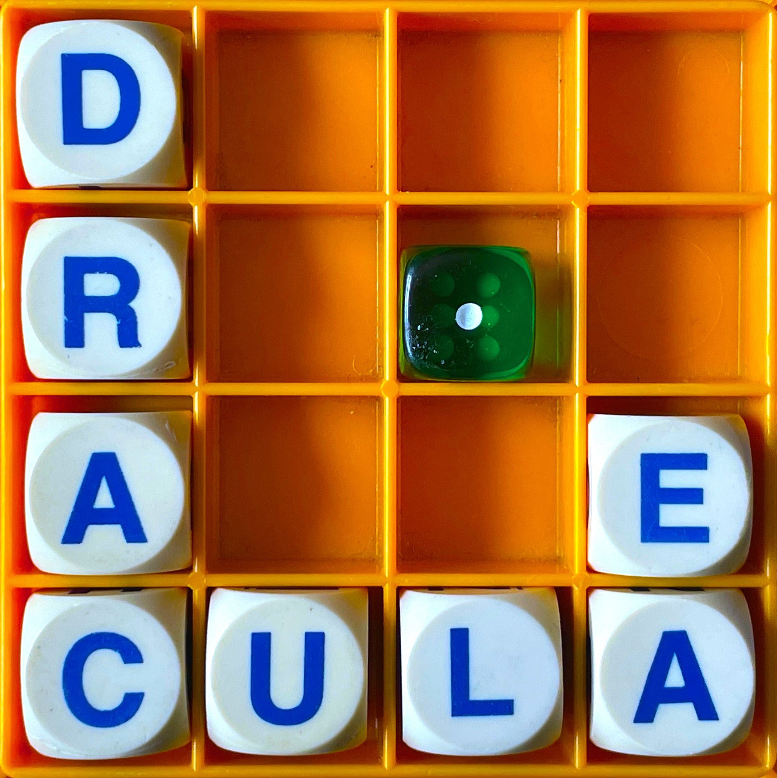 A boggle set spelling the word 'draculae' and with a green die showing the number 1