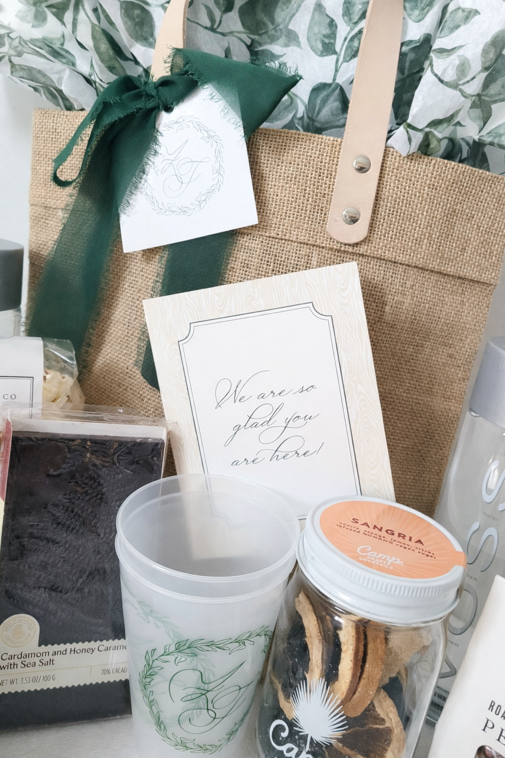 Luxury wedding welcome bag for an Auberge Mayflower Inn wedding in Washington, Connecticut with custom monogram tag, green silk ribbon, printed tissue paper and curated gourmet guest gifts.