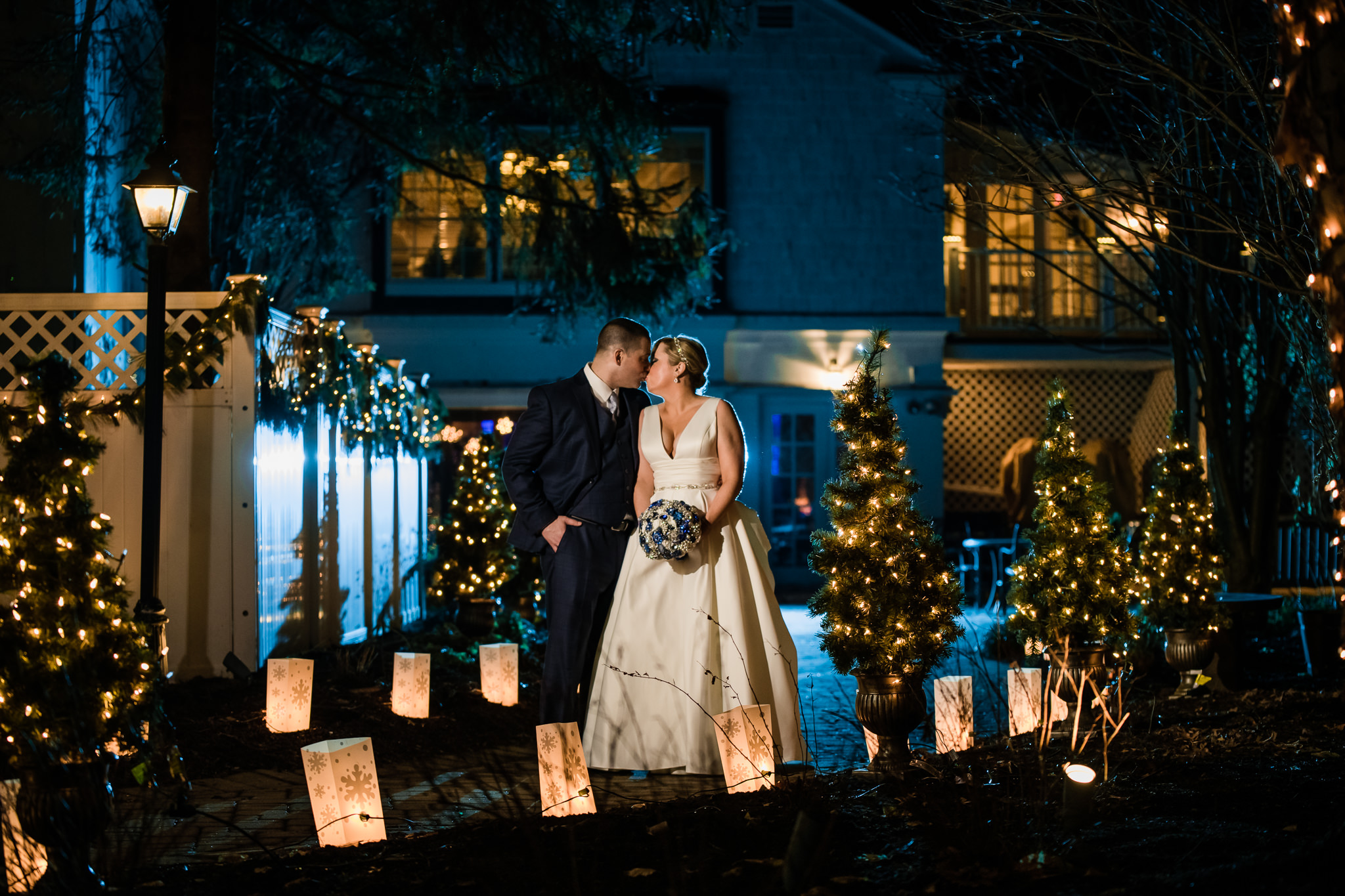 Bride and groom kissing during their winter wedding at the grain house in basking ridge new jersey with blue and orange Christmas themed lights