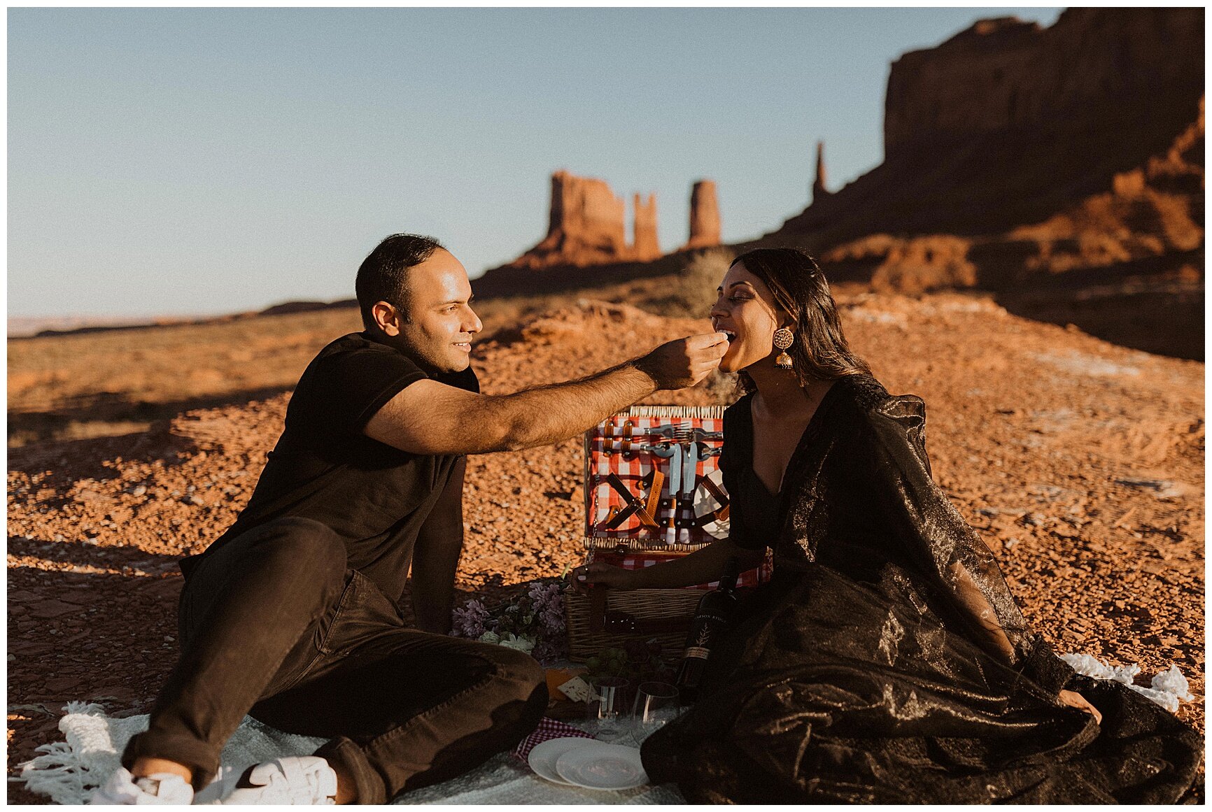 engaged couple having a picnic during their portrait session in monument valley, arizona