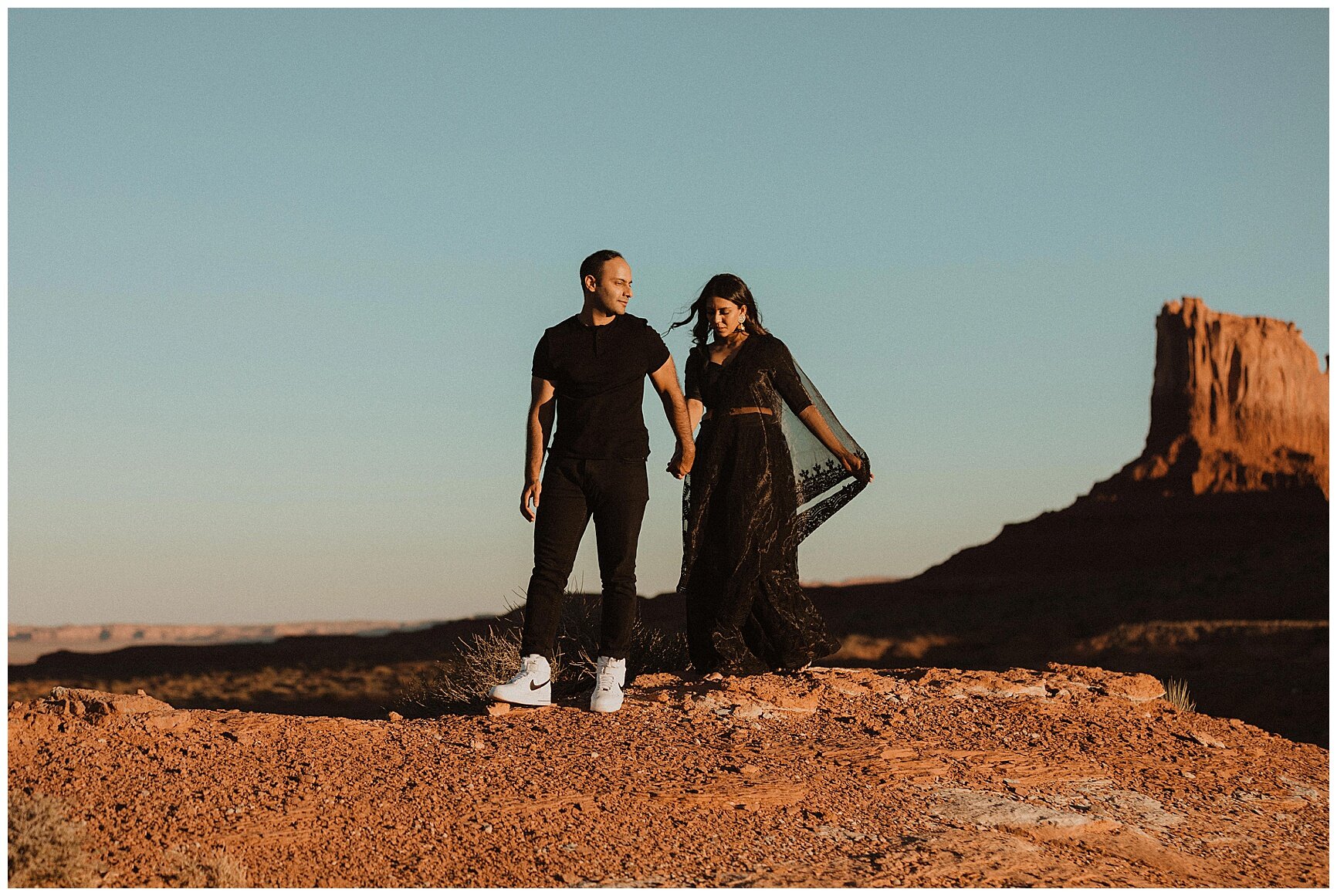 engaged couple holding hands and walking through the desertin monument valley, arizona