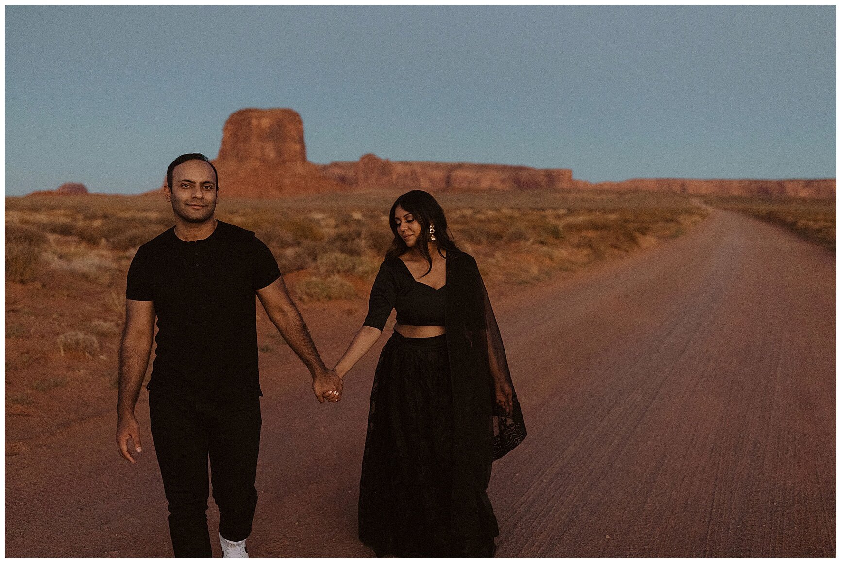 engaged couple holding hands and walking through the desert in monument valley, arizona