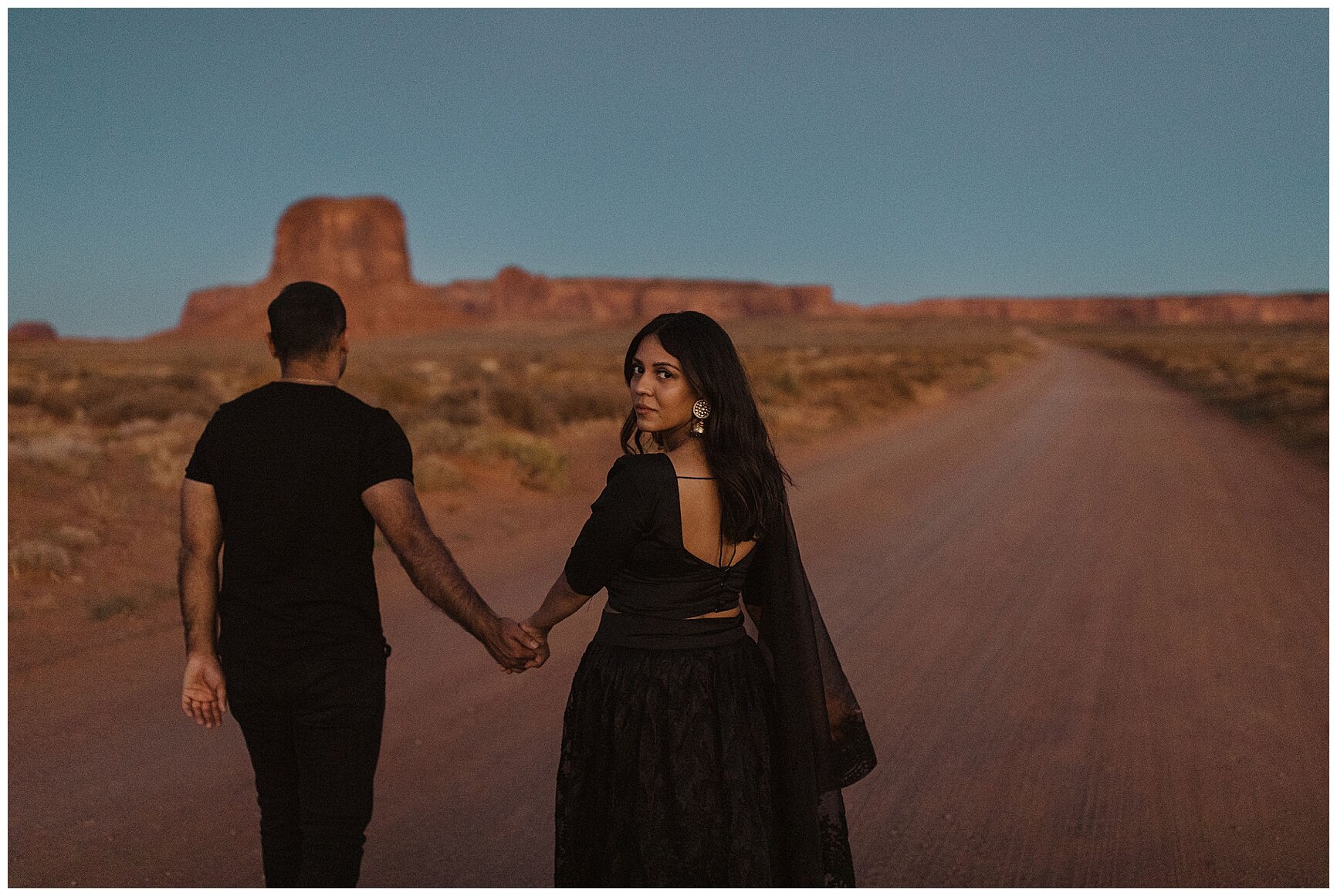engaged couple holding hands and walking through the desert in monument valley, arizona